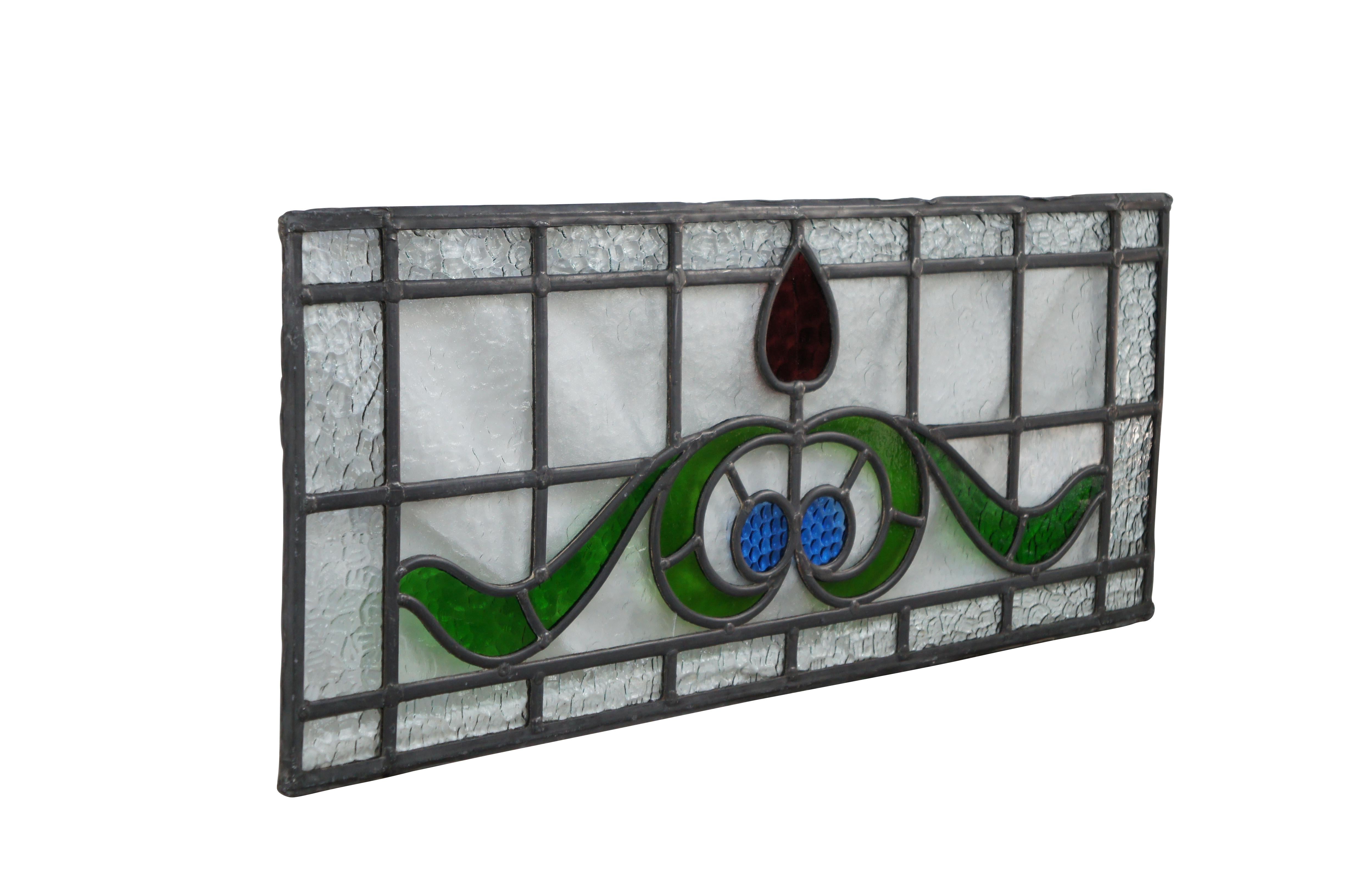 Magnifique vitrail ancien au plomb de style Art Nouveau. Le centre est orné d'une rose dans un ton rubis, de feuilles vertes et de cercles bleus sur un fond de verre galet. Parfait pour une utilisation au-dessus d'une porte.

Dimensions :
31