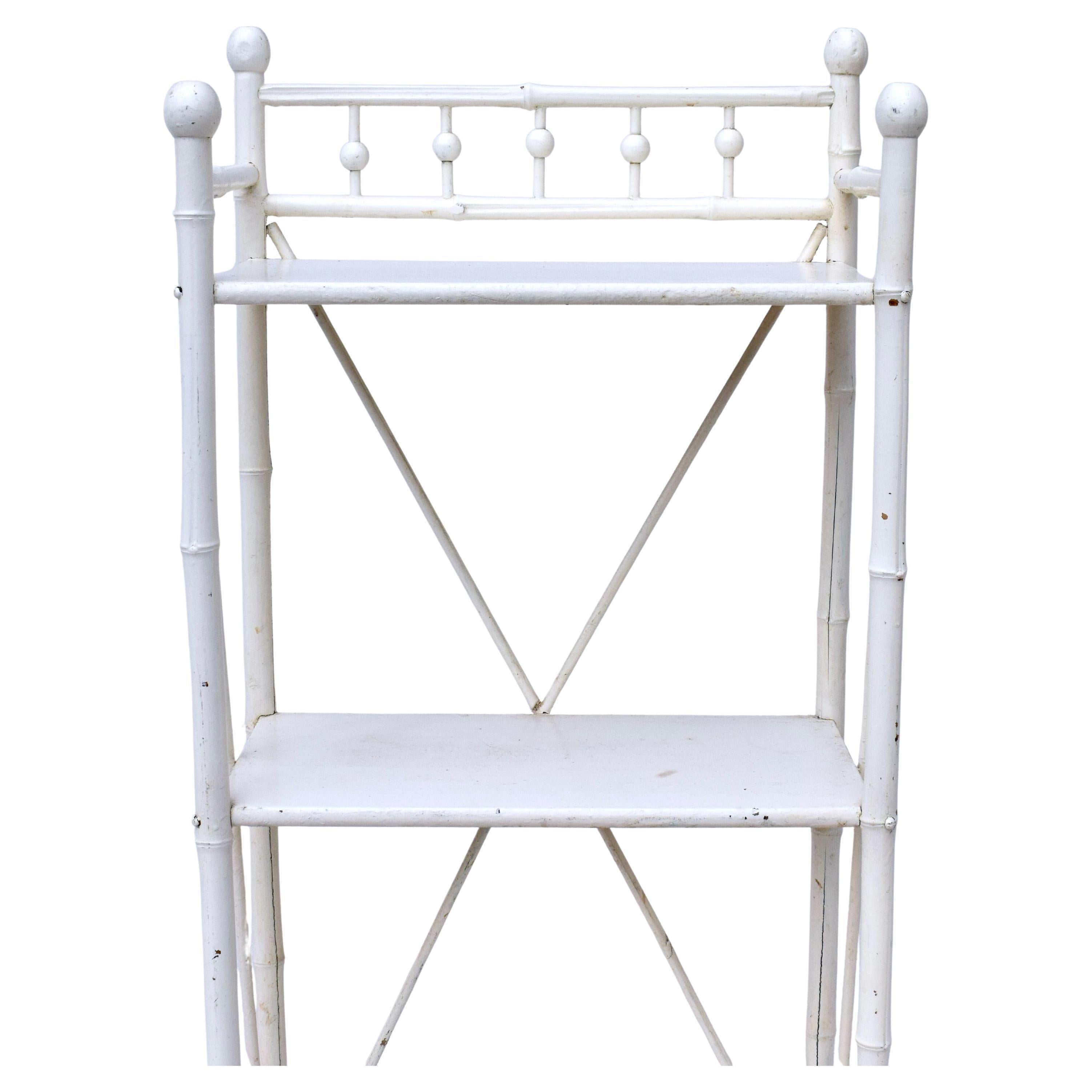 Étagère victoriana de finales del siglo XIX, con tres estantes de madera y un bastidor en forma de X en la parte trasera y los laterales que garantiza una construcción sólida. Pintura blanca patinada bien conservada en un acabado naturalmente