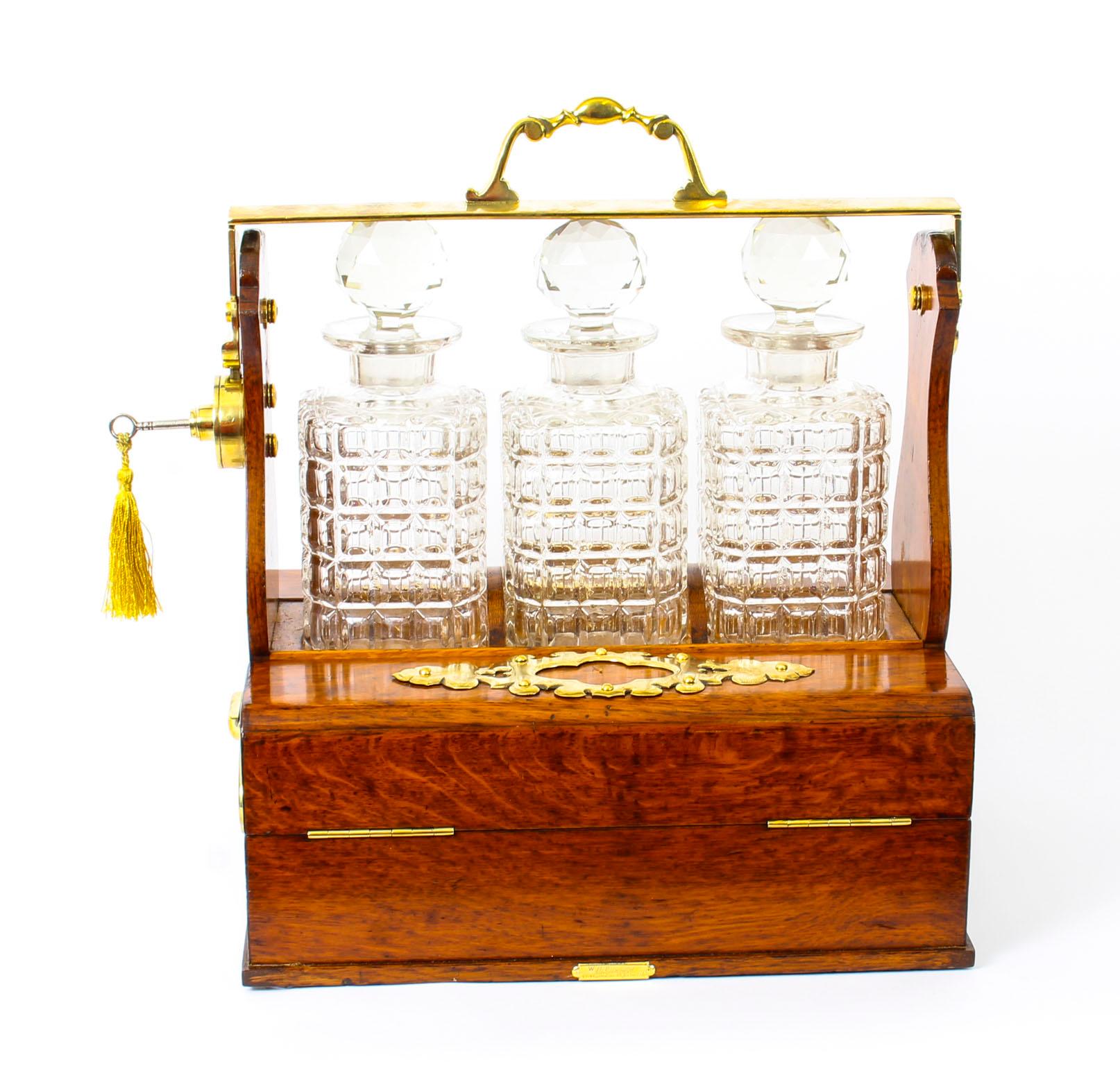 This is a superb antique Victorian Betjemans oak cased three decanter tantalus and humidor, late 19th century in date.

It was skillfully crafted in tiger oak with beautiful brass mounts and stylish handles. The locking swing brass handle above