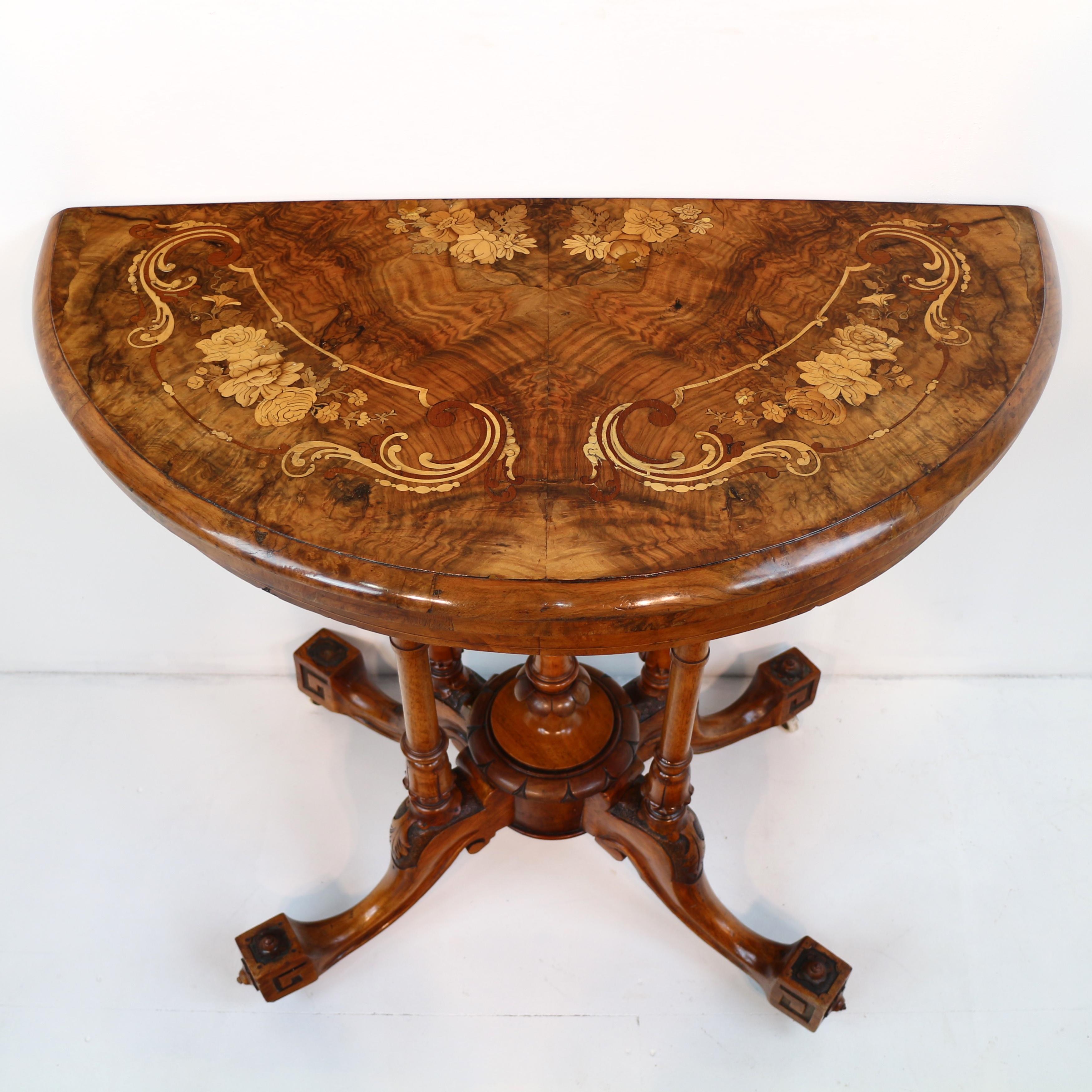 An attractive `Victorian walnut and marquetry demi-lune card table dating to circa 1870.  The fold-over top inlaid with sprays of flowers within scrolling borders, with a thumb moulded edge above a line inlaid frieze and supported by four turned