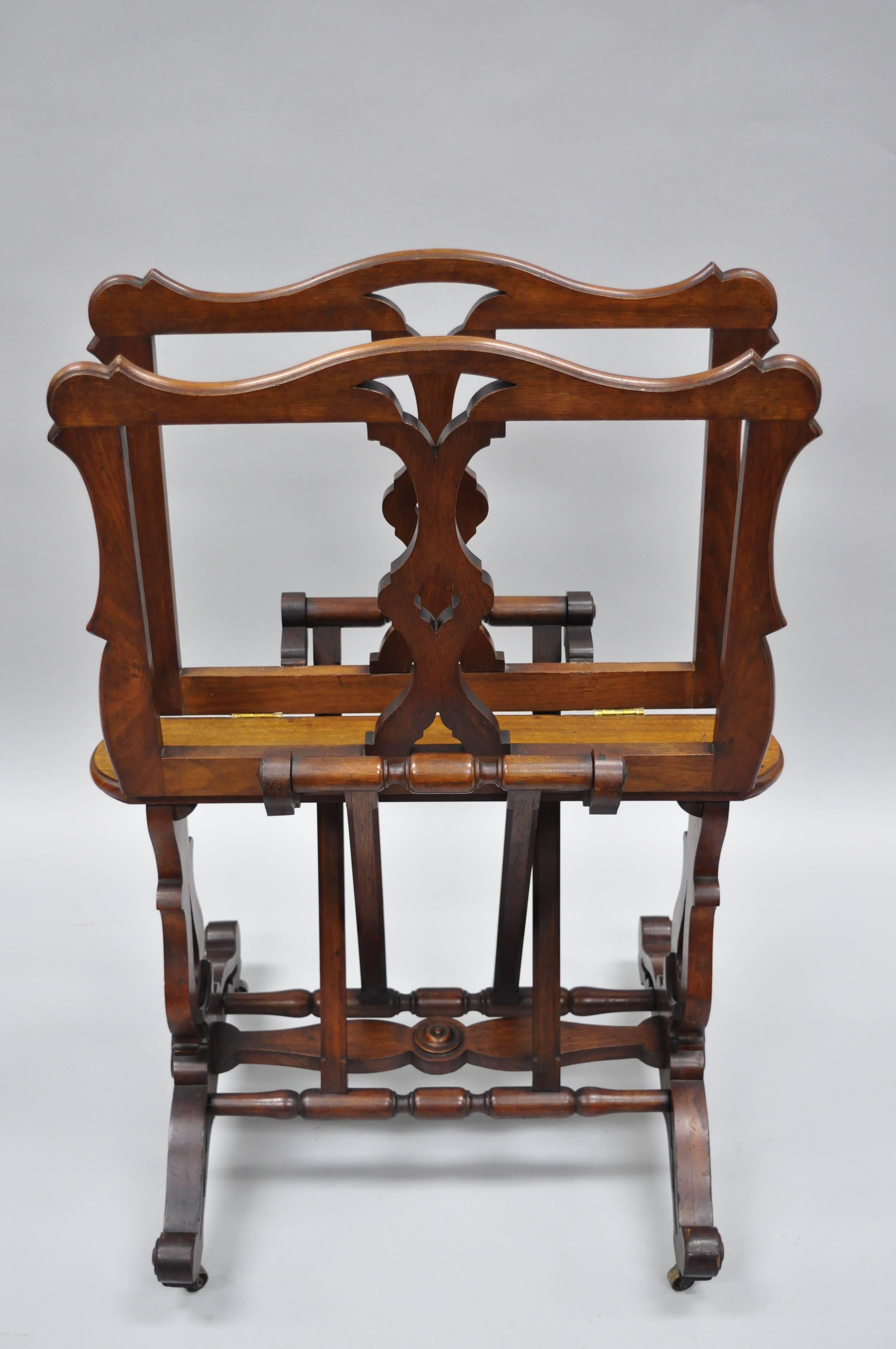 Antique English Victorian carved walnut adjustable print or book stand. Item features four adjustable settings, two hinged racks, solid carved walnut frame, brass rolling casters, groove adjustments at base. Rare antique item, circa late 19th