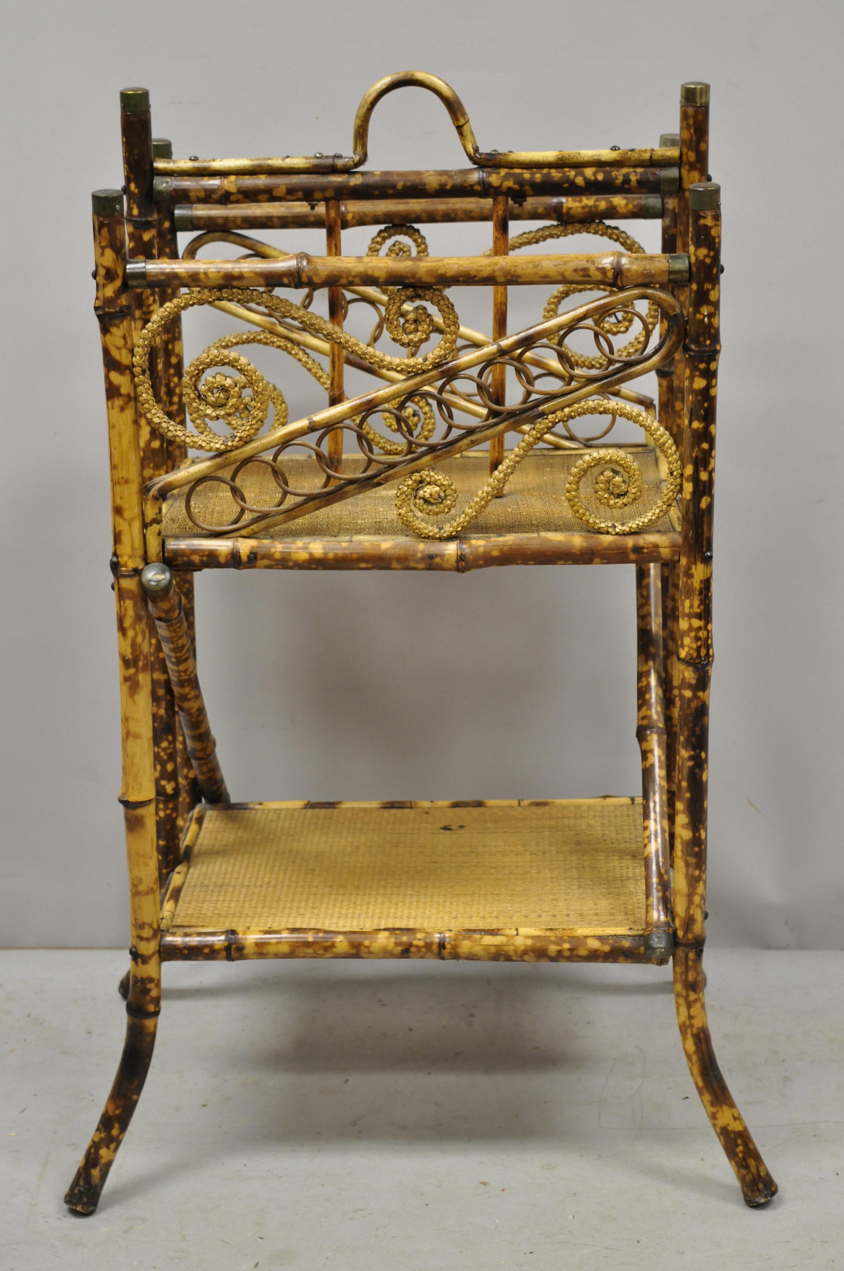 Antique English Victorian charred burnt bamboo magazine rack stand shelf. Item features ornate bent bamboo scrollwork, lower shelf, brass accents, very rare model, very nice antique item, circa early 20th century. Measurements: 37.5