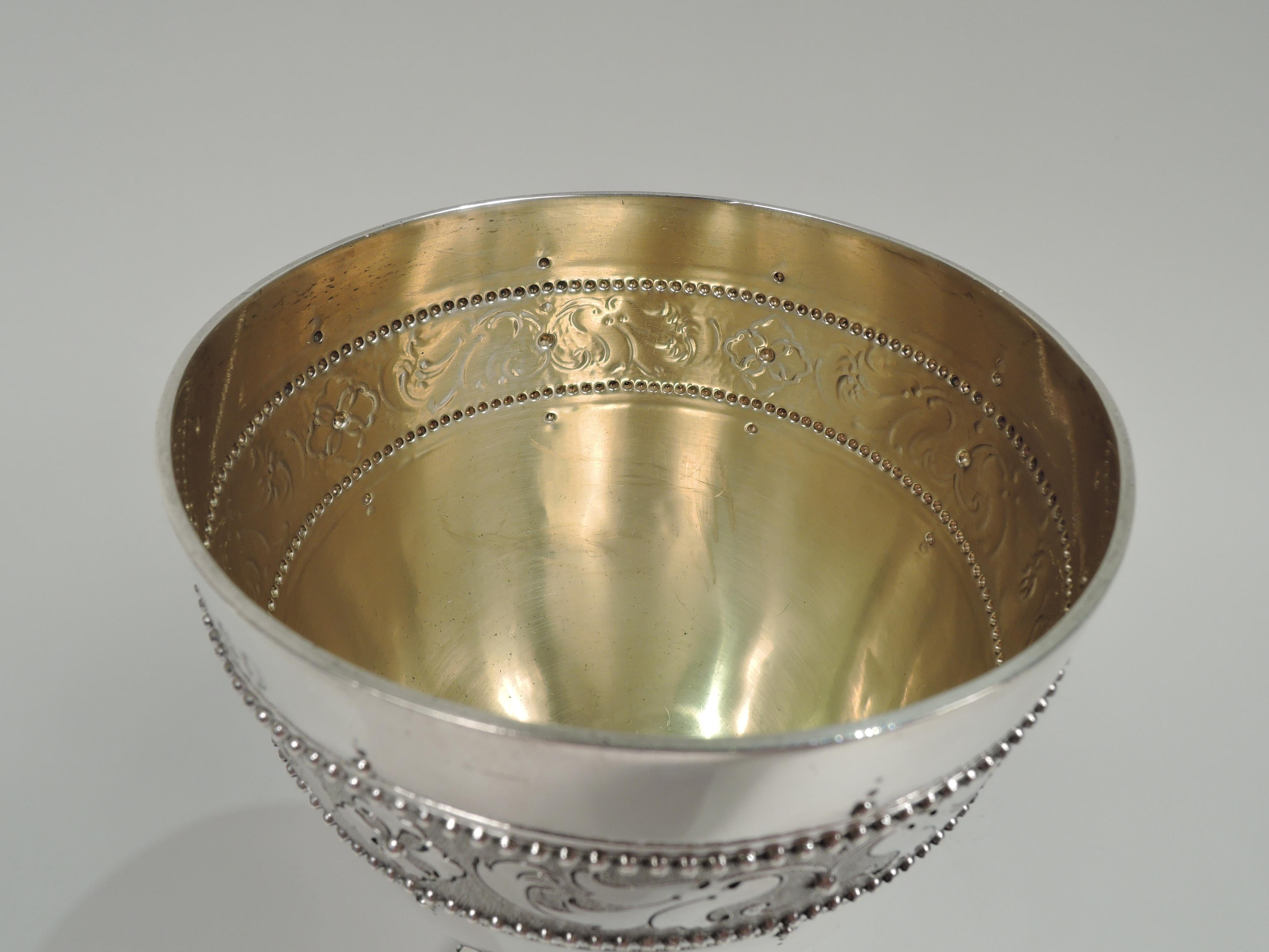 Victorian Classical sterling silver goblet. Made by Edward Charles Brown in London in 1879. Oval bowl in knopped and cylindrical support flowing into round foot. Scrolling leaf and flower borders on stippled ground. Beading. Gilt-washed interior.