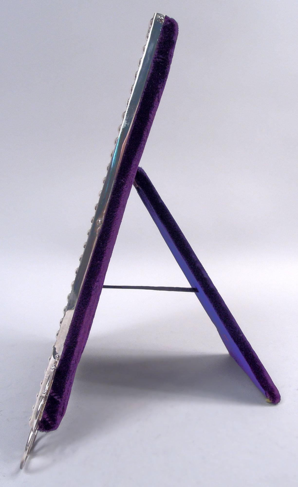 Cornice classica vittoriana in argento sterling, 1898. Contorno rettangolare con bordo a basso rilievo a forma di uovo e dardo; lati lisci. Corona e supporti a volute aperte. Con vetro smussato, fodera in seta, dorso in velluto e supporto a