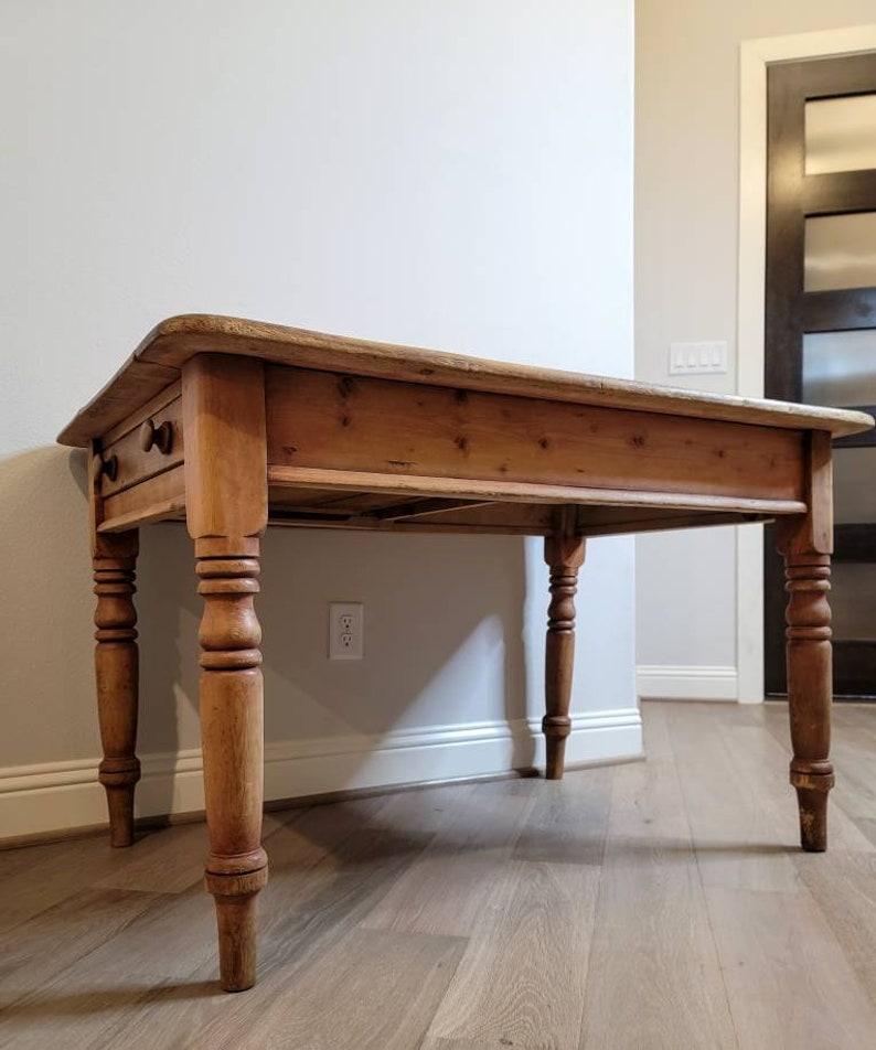 A rustic country English Victorian farmhouse kitchen work table, hand-crafted of solid pine, dating to the 19th century, having a rectangular three board plank top, over a single drawer, rising on turned legs. Featuring a distinctive, beautifully