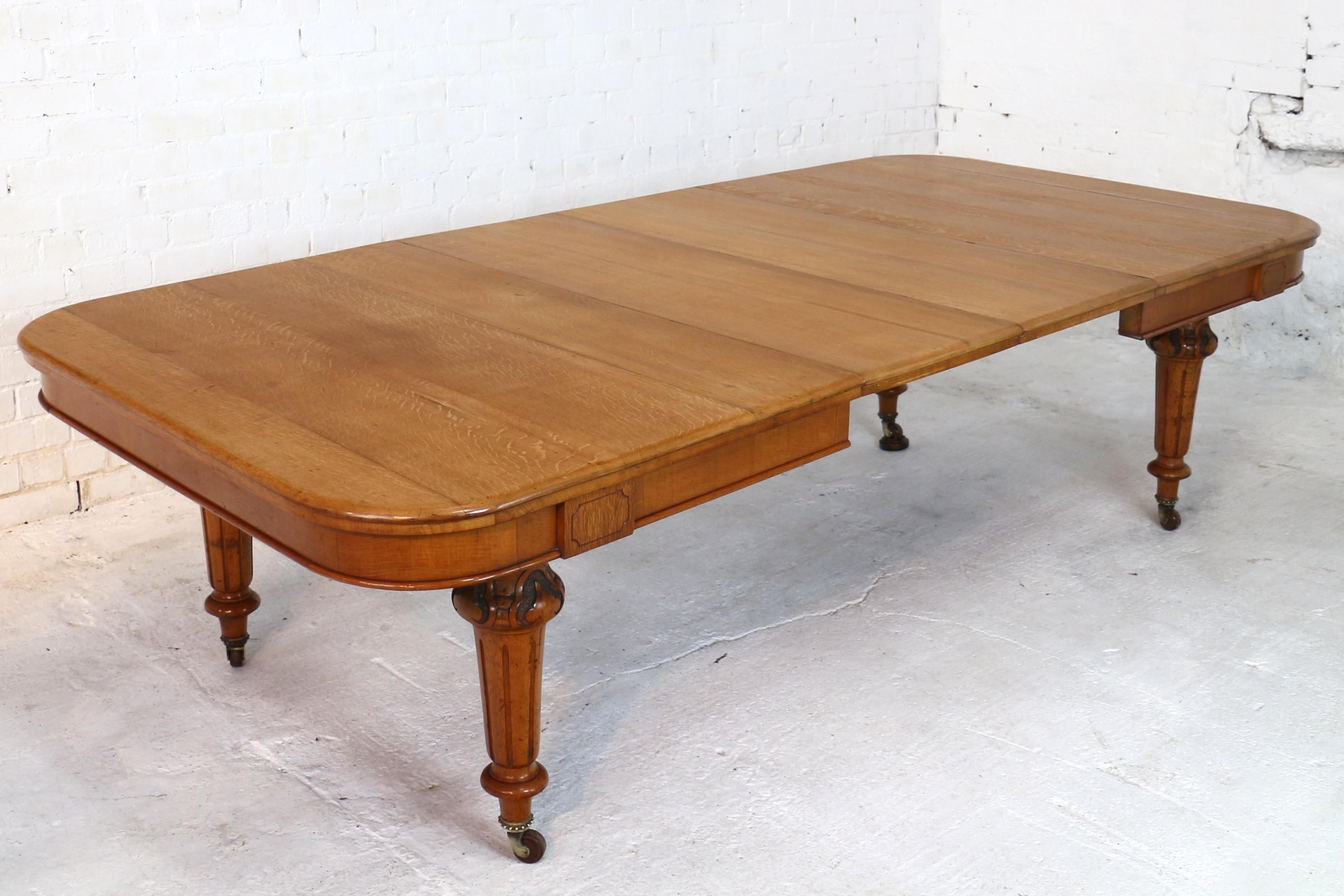 An attractive Victorian extending dining table in light golden quarter-sawn oak with two original leaves and dating to circa 1870. The rounded rectangular top with a moulded edge and decorative tablet above each carved and fluted turned leg,