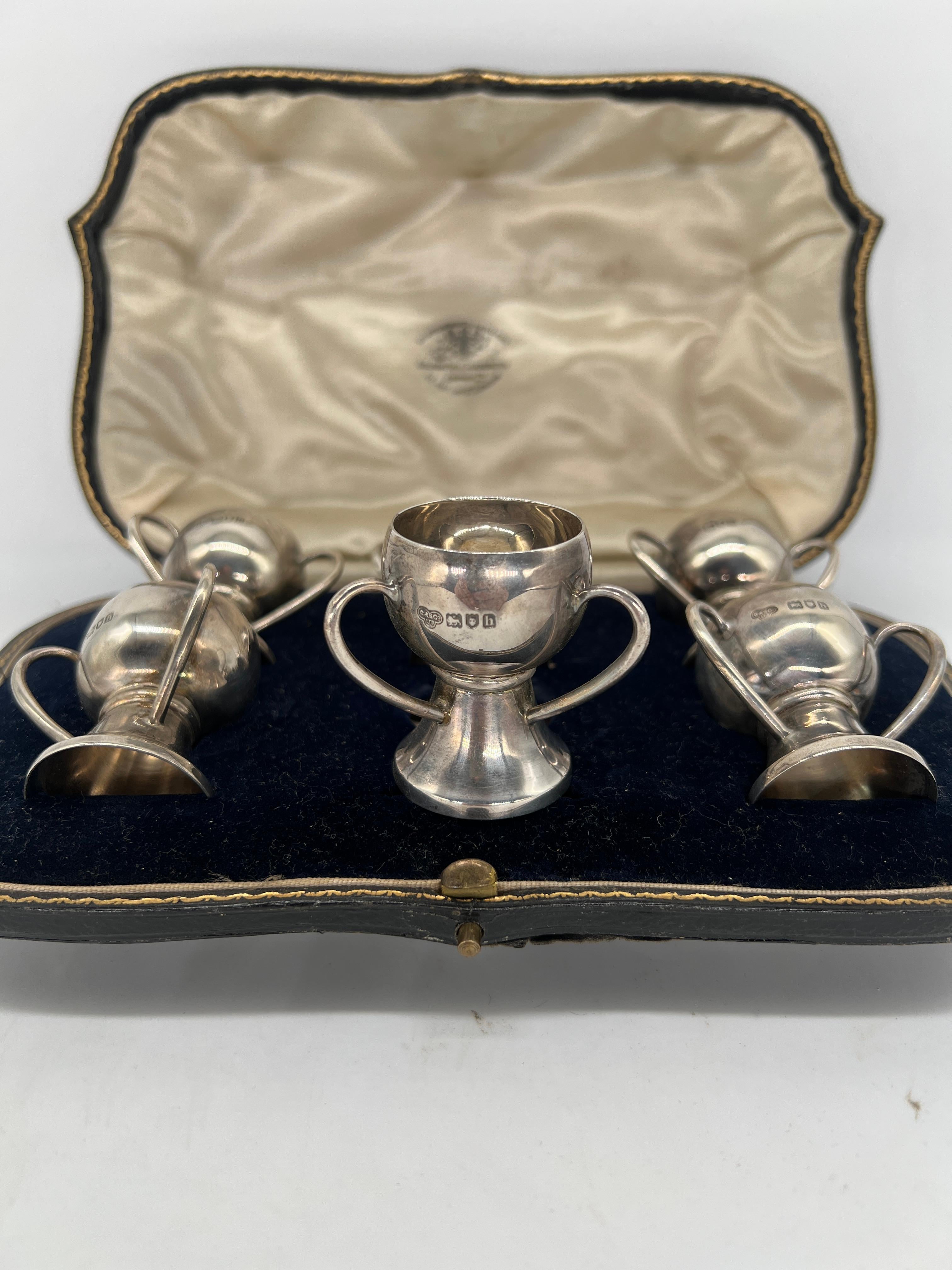 Ce rare ensemble de sels en forme de trophée en argent sterling de l'époque victorienne a été fabriqué par la célèbre société anglaise Goldsmiths & Silversmiths Company. Présenté dans son étui d'origine ajusté et doublé, chaque sel présente une
