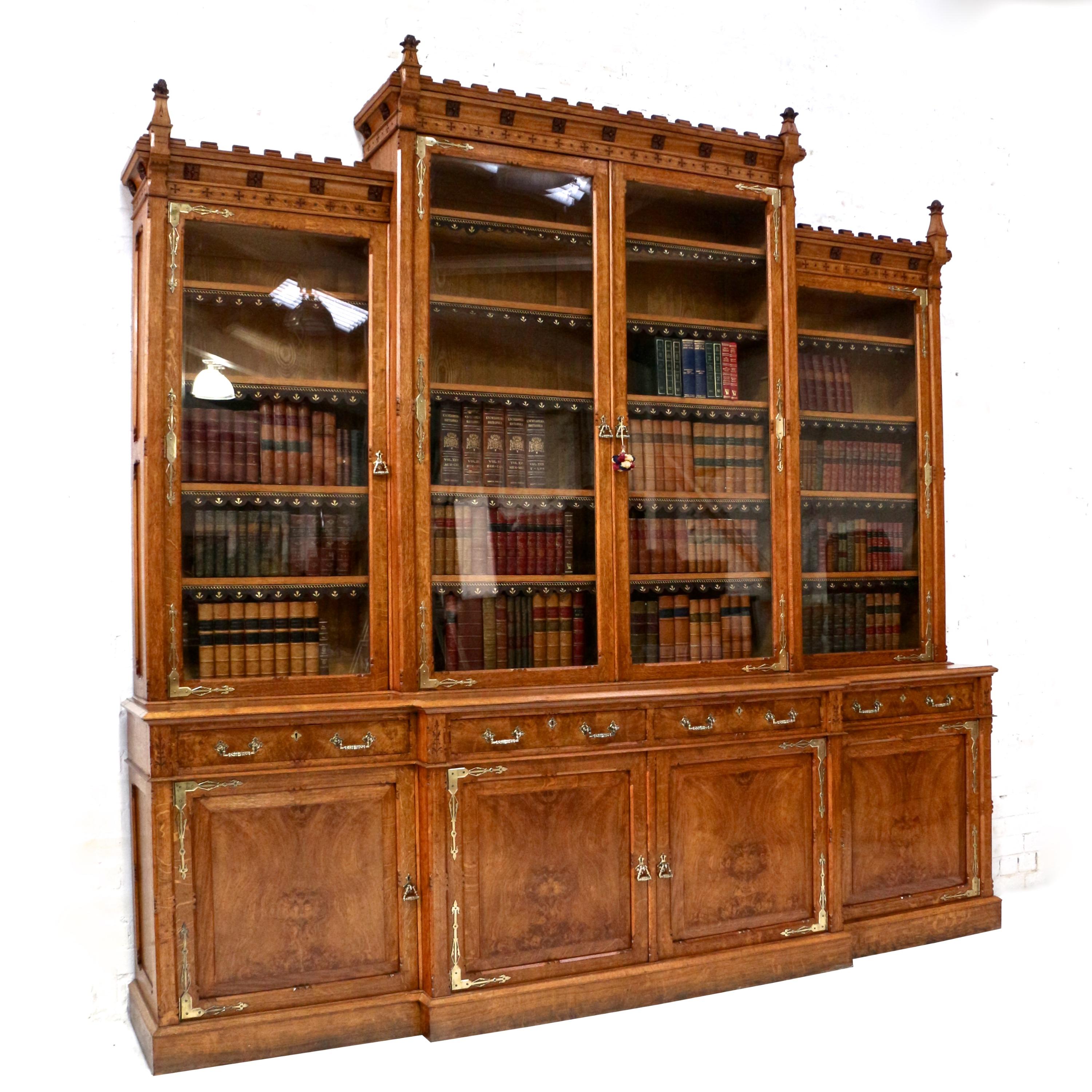 An impressive Gothic Revival oak and pollard oak four door breakfront bookcase in the Pugin style and attributed to Gillows of Lancaster. Dating to circa 1860 this superb library bookcase features a stepped castellated cornice with tapering stylised
