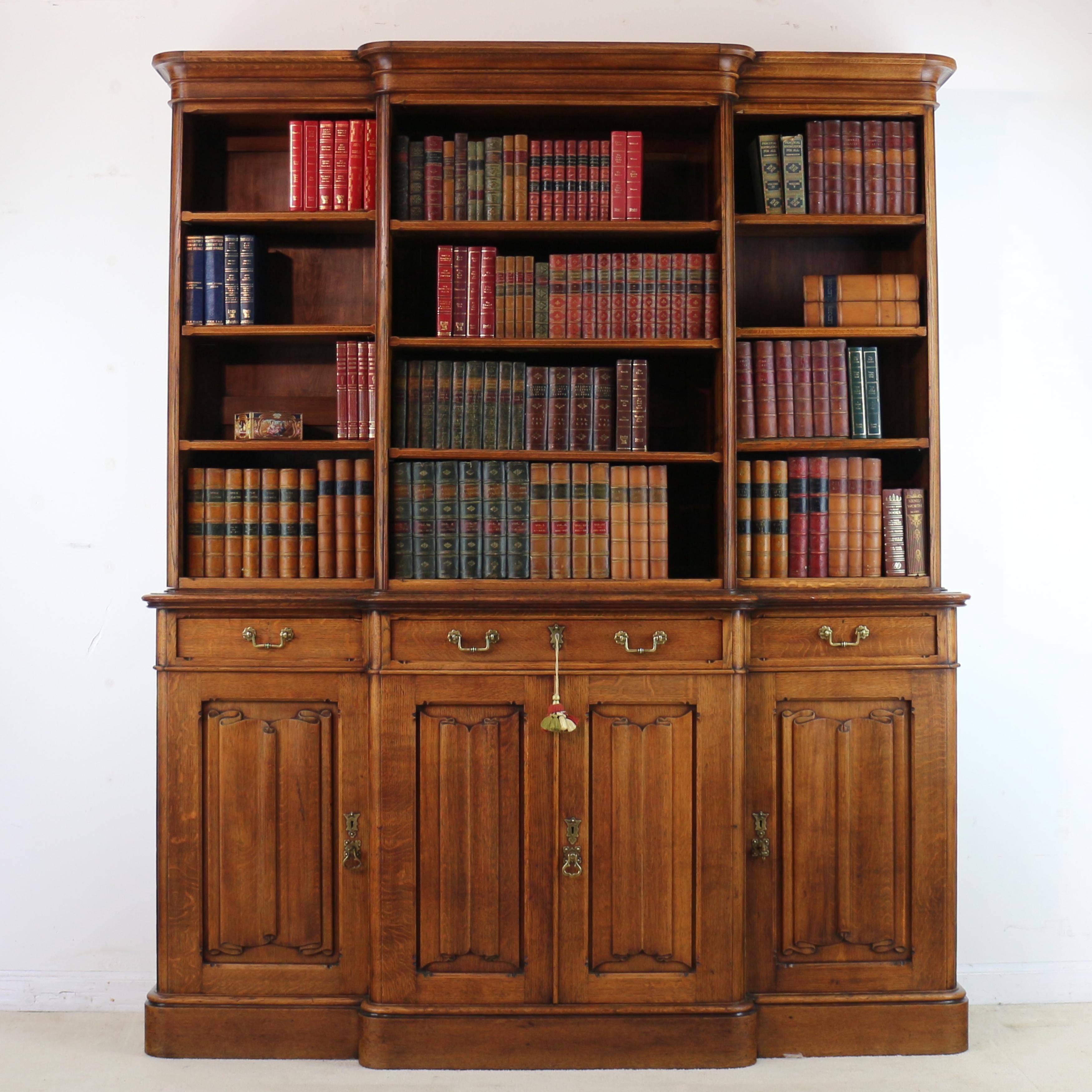 A Victorian Gothic Revival quarter sawn oak breakfront bookcase in the Pugin style and attributable to Gillows of Lancaster. This super Arts & Crafts bookcase features crisply carved linenfold panels and Gothic brass handles and backplates. With a