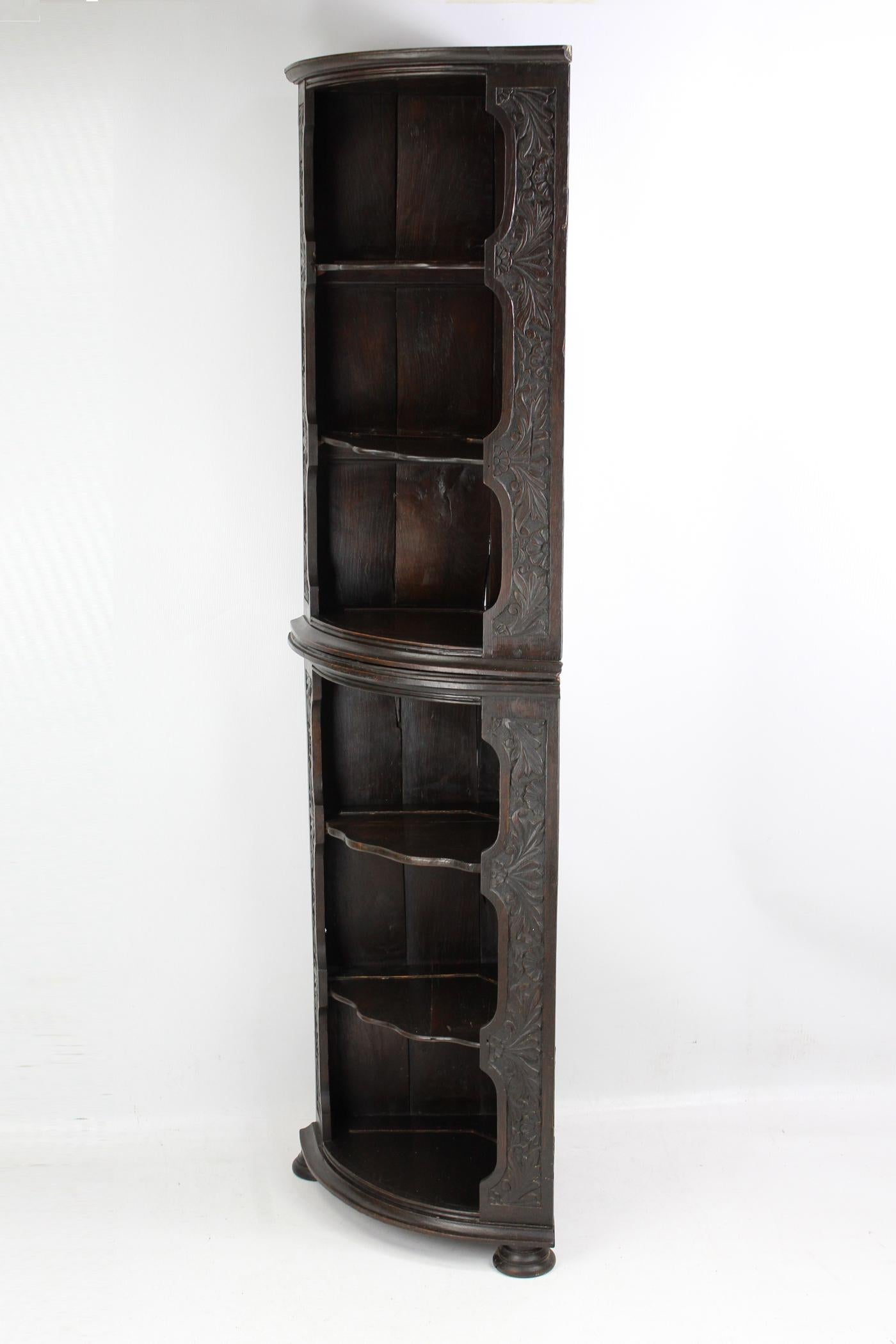 A magnificent antique Victorian Gothic Revival corner shelf unit in carved oak dating from circa 1880. In two sections, with open bow fronts the sides shaped and carved with moulded cornices to the top and bottom. It has six shelves, four of which