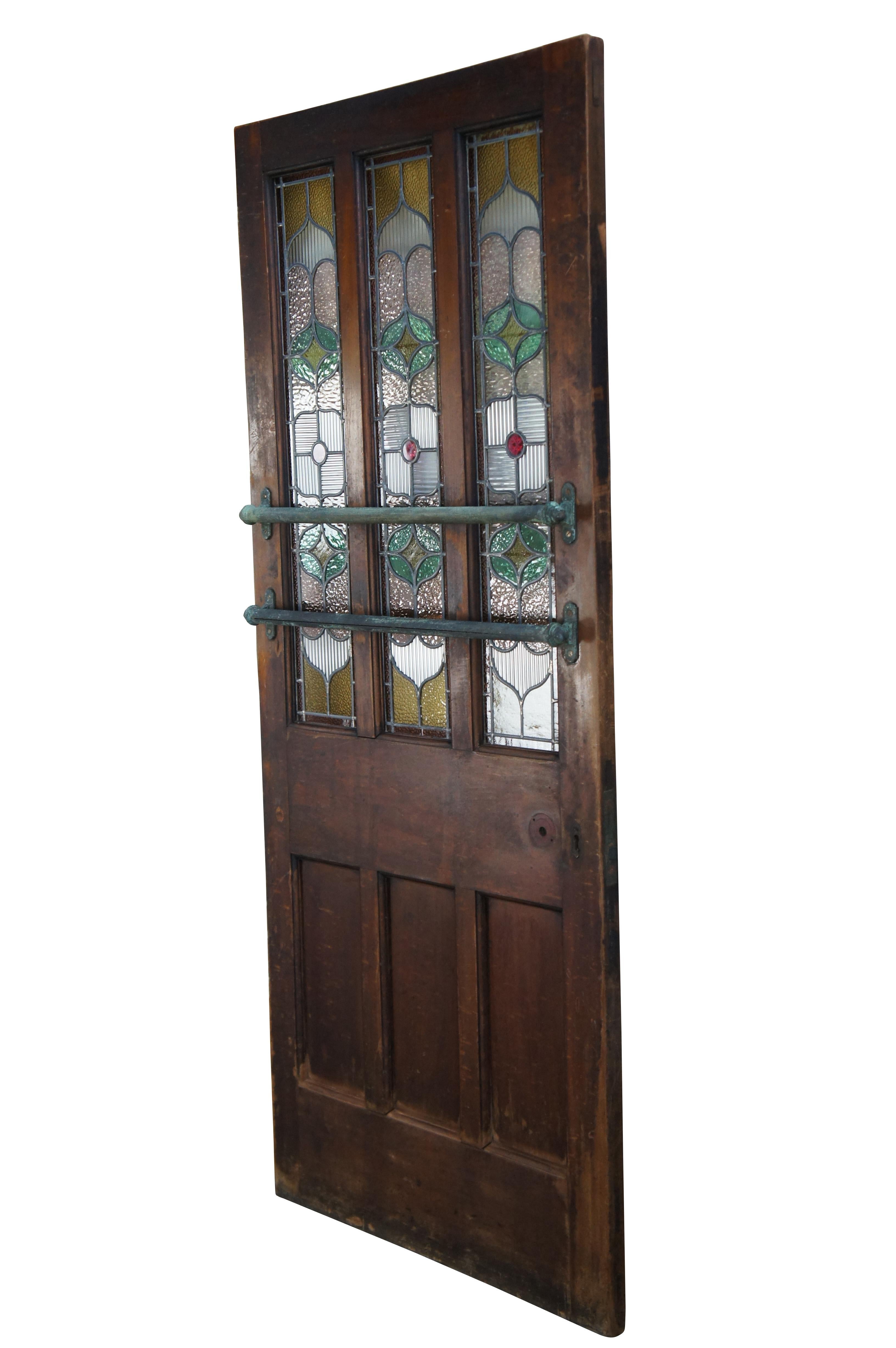 An exquisite 19th century stained glass door reclaimed from a Pub in London, England. Features a large solid mahogany paneled frame with three half glazed leaded stained glass windows. Each window showcases pebbled and ribbed textured clear glass