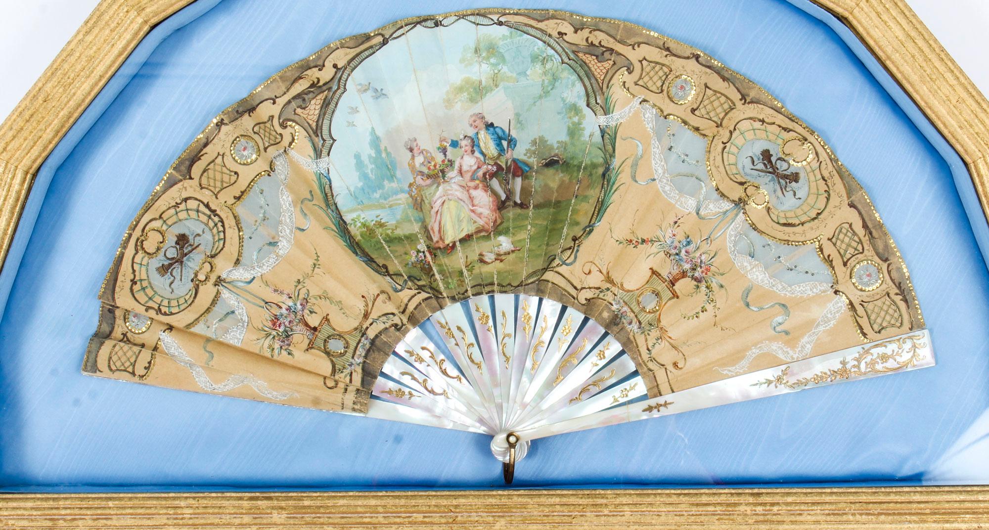This is a stunning antique English Victorian hand painted and mother of pearl fan set in a gilded frame, dating from the late 19th Century.

The fan is beautifully hand painted with a central cartouche featuring a lovely rustic scene of young