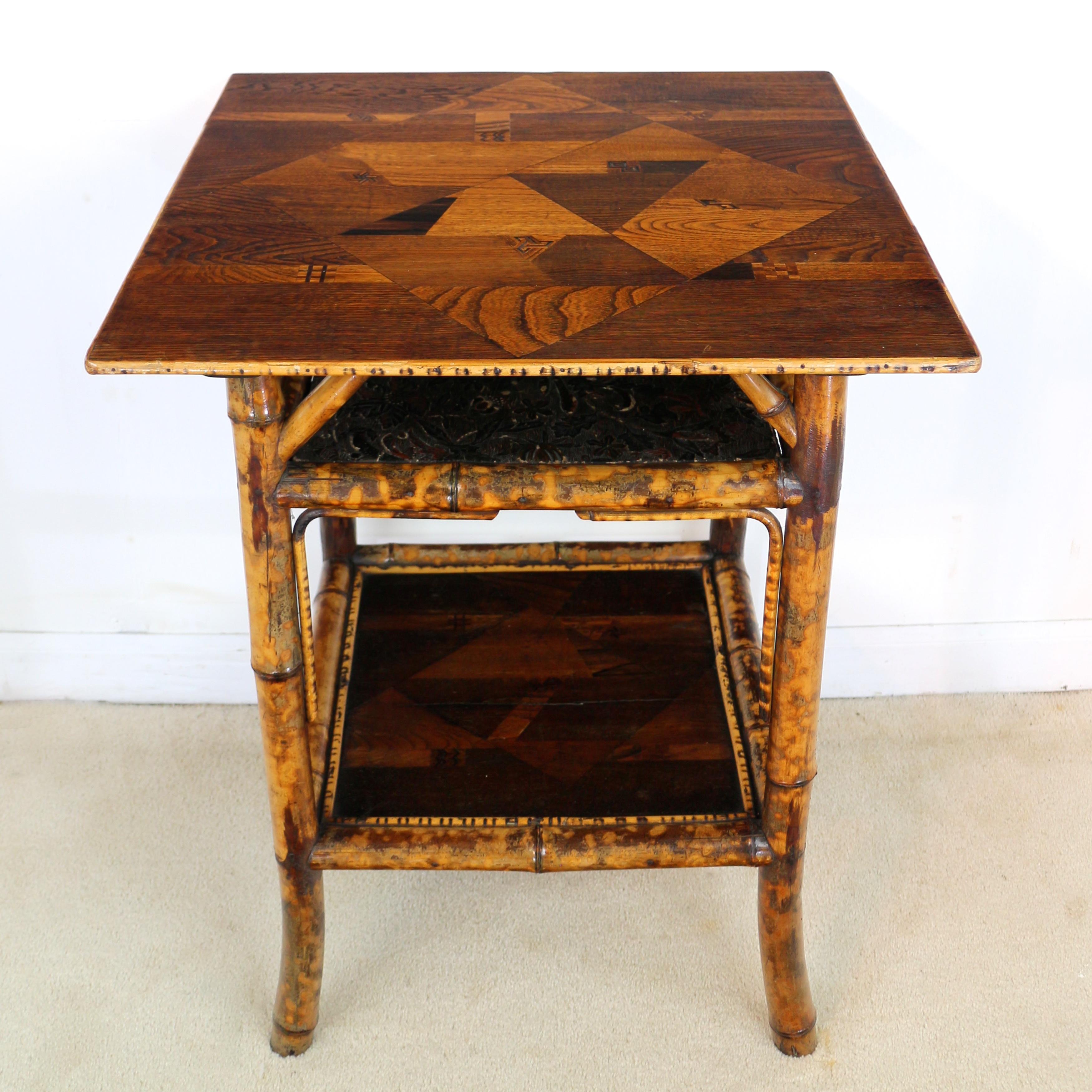 An unusual late Victorian bamboo occasional table with a Japanese parquetry top and bamboo supports with simulated tortoiseshell colouring. The cane edged square top inlaid with a geometric design in various specimen woods and similarly inlaid lower