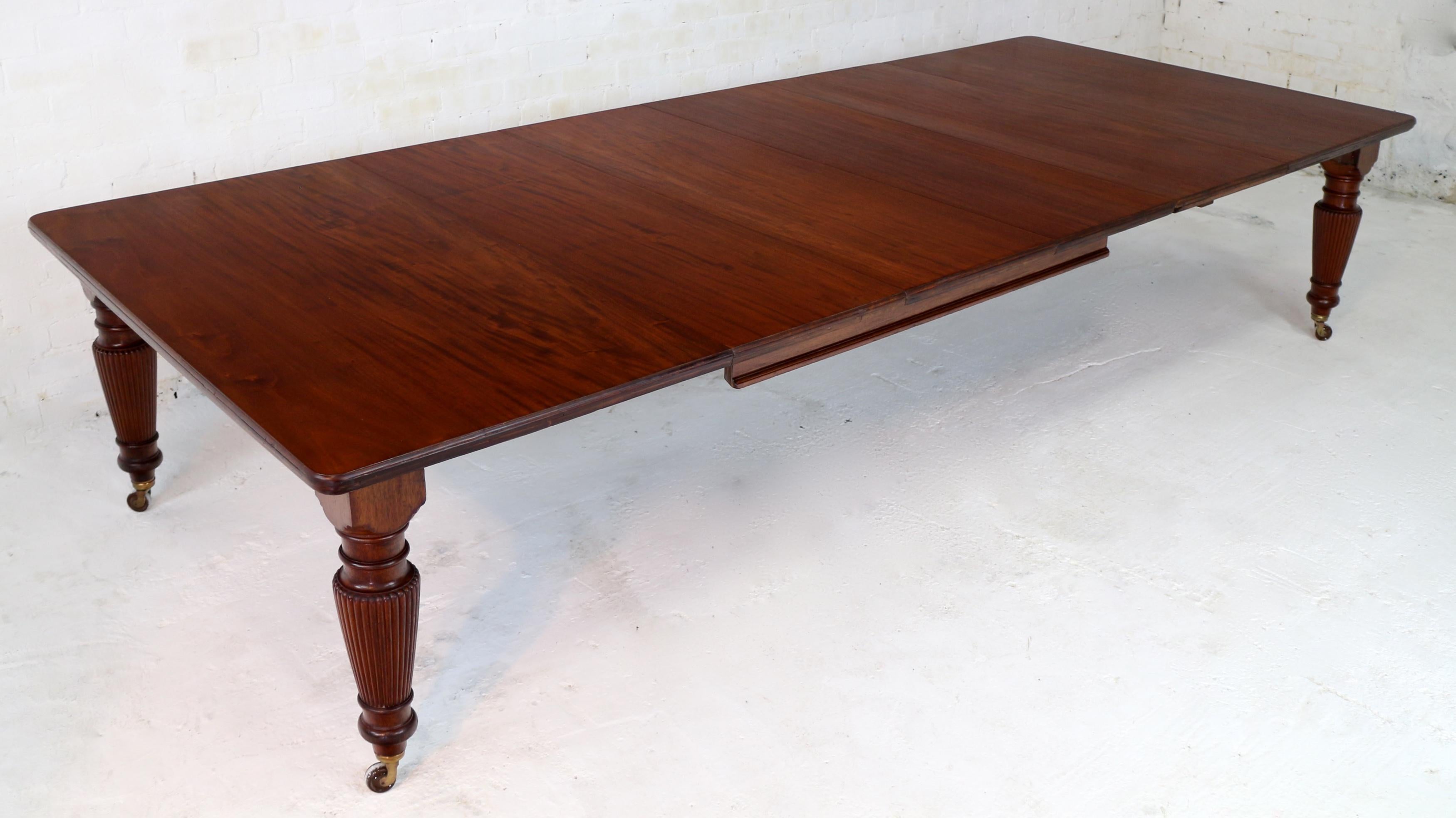 A super quality antique Victorian flame mahogany wind-out extending dining table with four additional leaves and standing on four finely reeded and turned tapering legs. This large 5ft wide table smoothly extends from 5ft 4.5in to just under 12ft by
