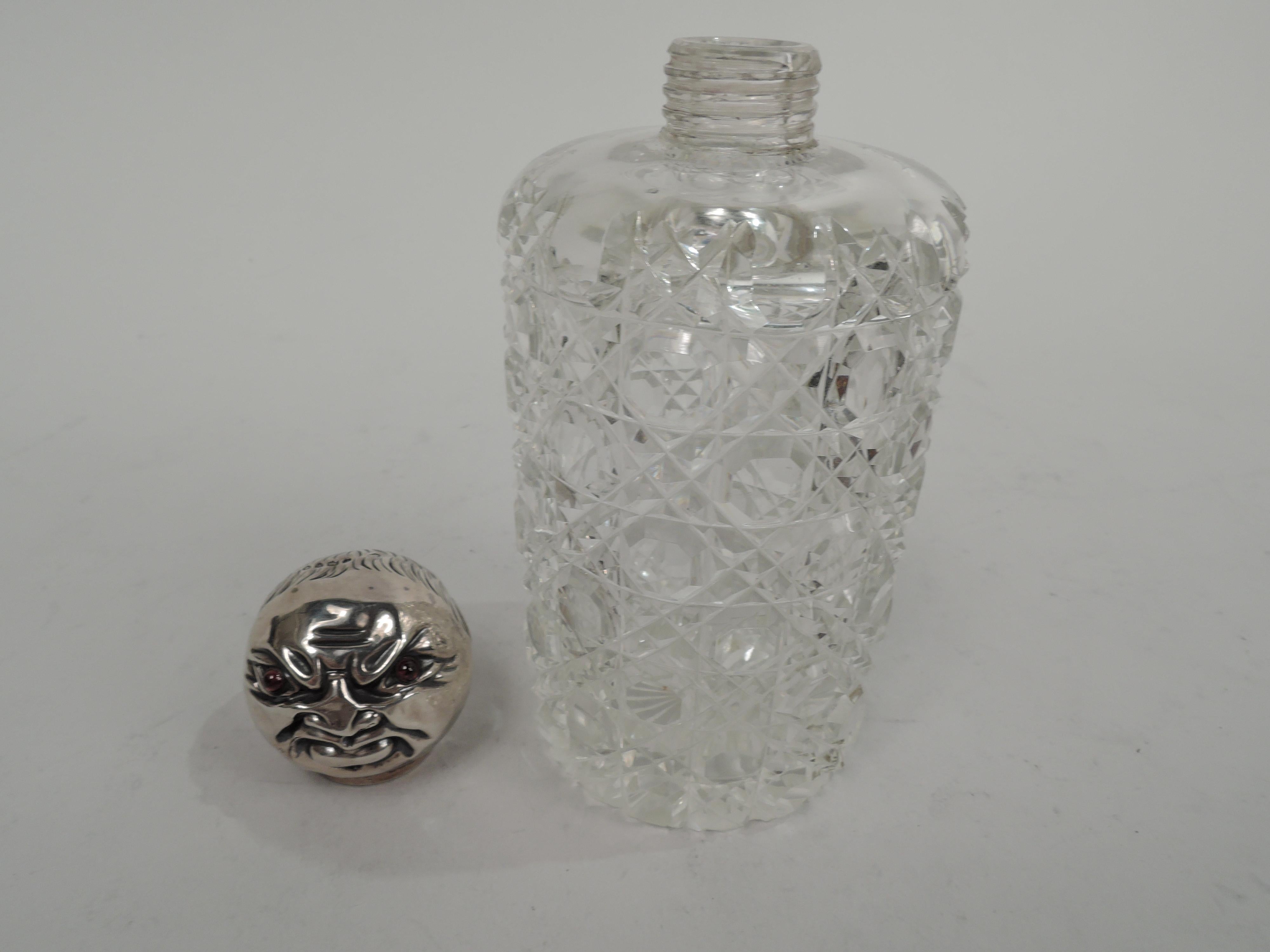 English Victorian cologne bottle, 1880. Cut-glass cylinder with short and threaded inset neck. Ball cover in form of male head with big ears, receding hairline, tronie-style grimace, and red bead eyes. Fully marked including London assay stamp and