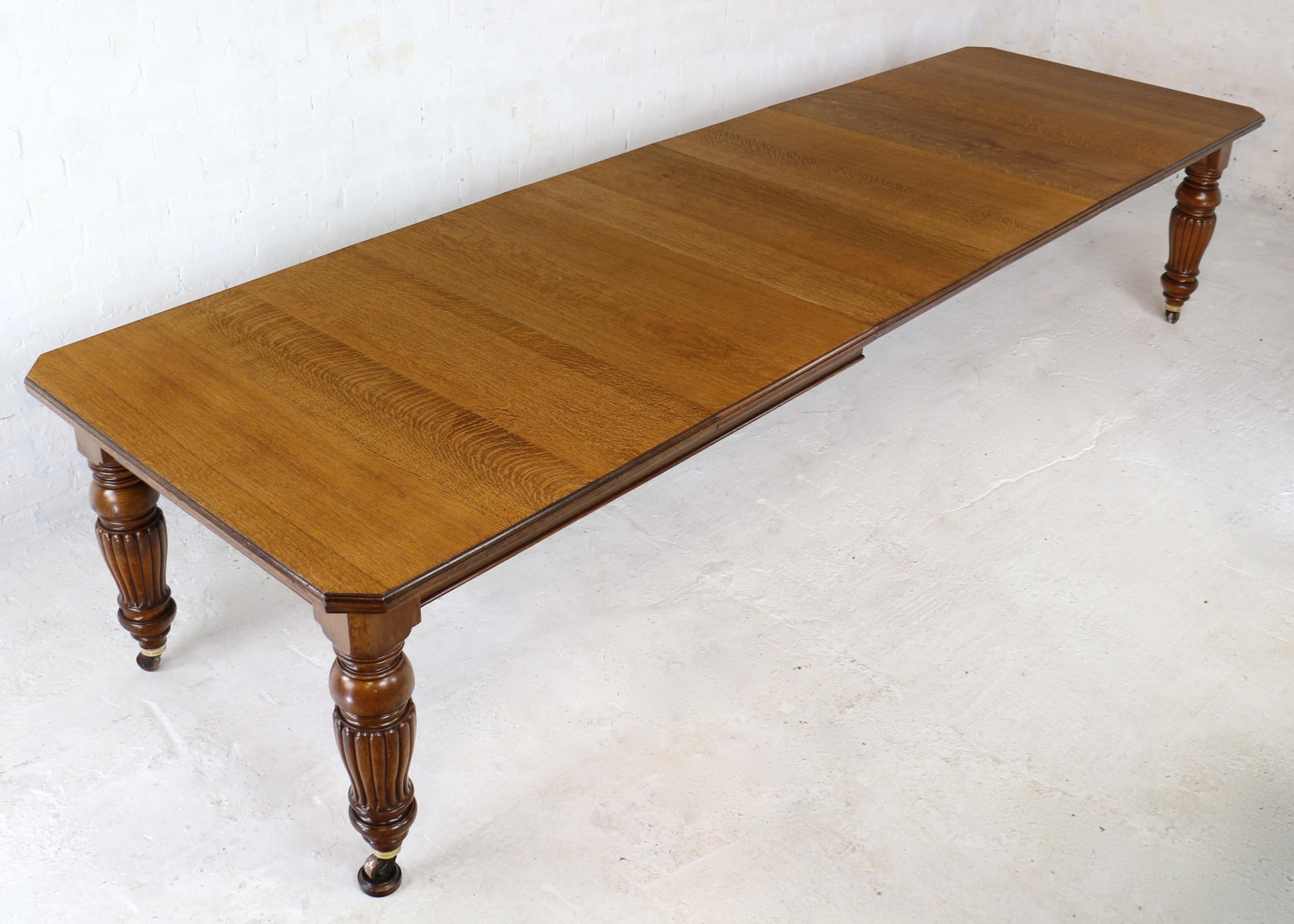 A super late Victorian wind-out extending dining table in quarter-sawn oak and made by Selbat. With a rectangular top with canted or cut corners and an ovolo moulded edge it stands on four turned and reeded tulip shaped legs with brass caps and rare