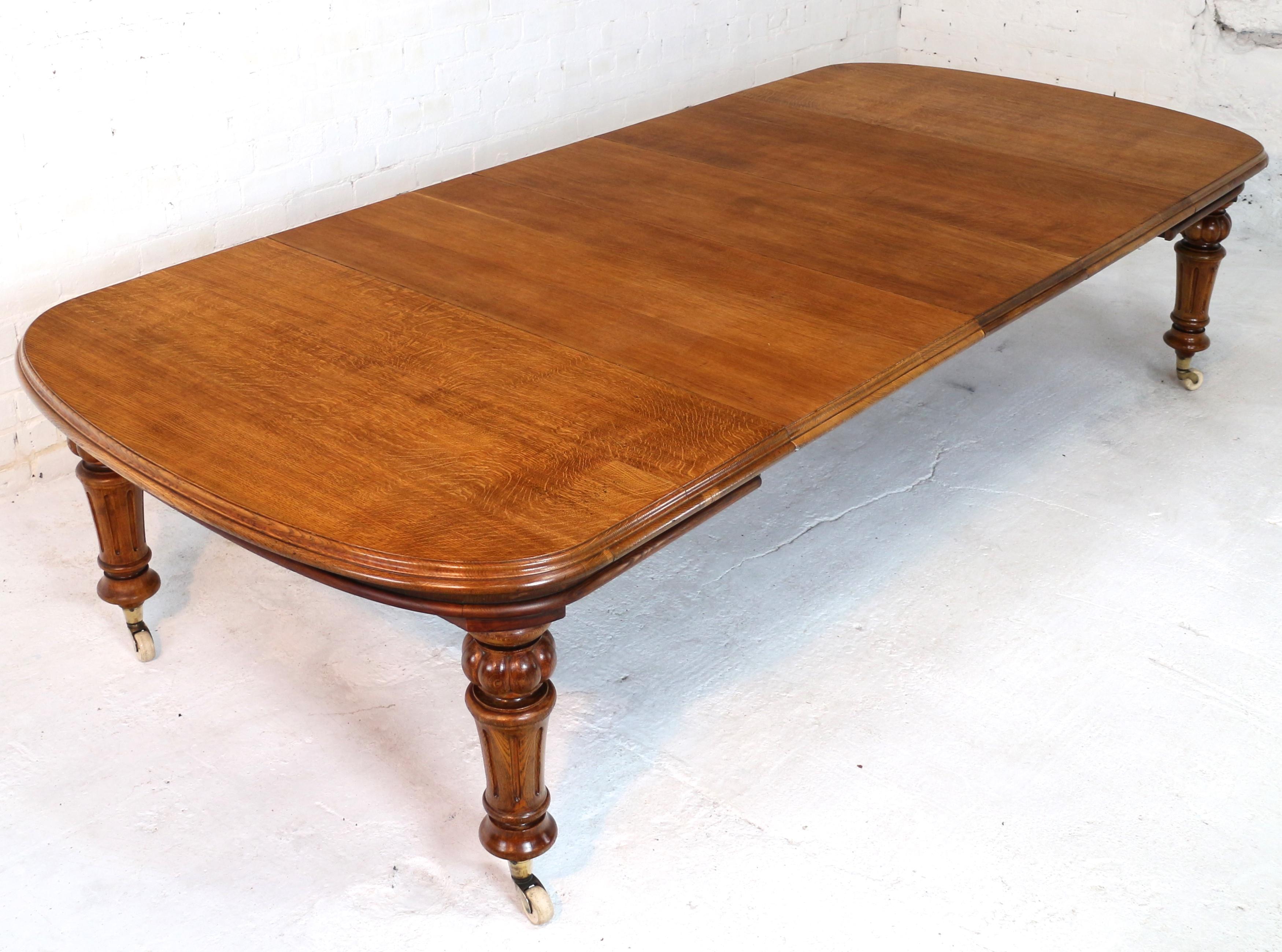 A super Victorian extending dining table in golden quarter-sawn oak with three original leaves and dating to circa 1870. The D-ended rectangular top with a double molded edge and standing on four reeded and fluted turned legs with brass caps and