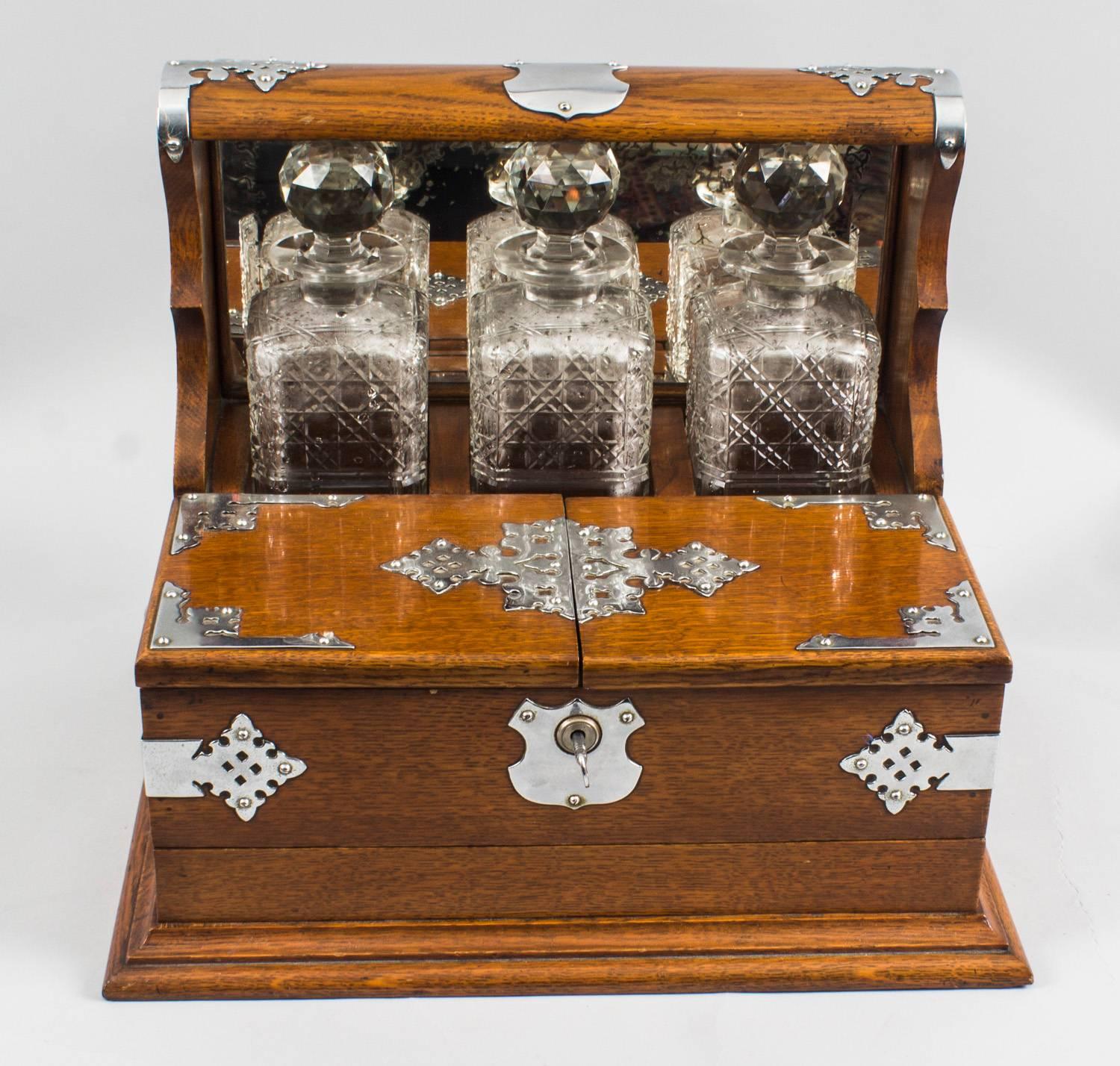 This is a superb antique Victorian oak cased three decanter tantalus with decorative cut brass silver plated mounts, circa 1870 in date.

It was skillfully crafted in tiger oak with beautiful silver plated mounts and stylish handles. There are