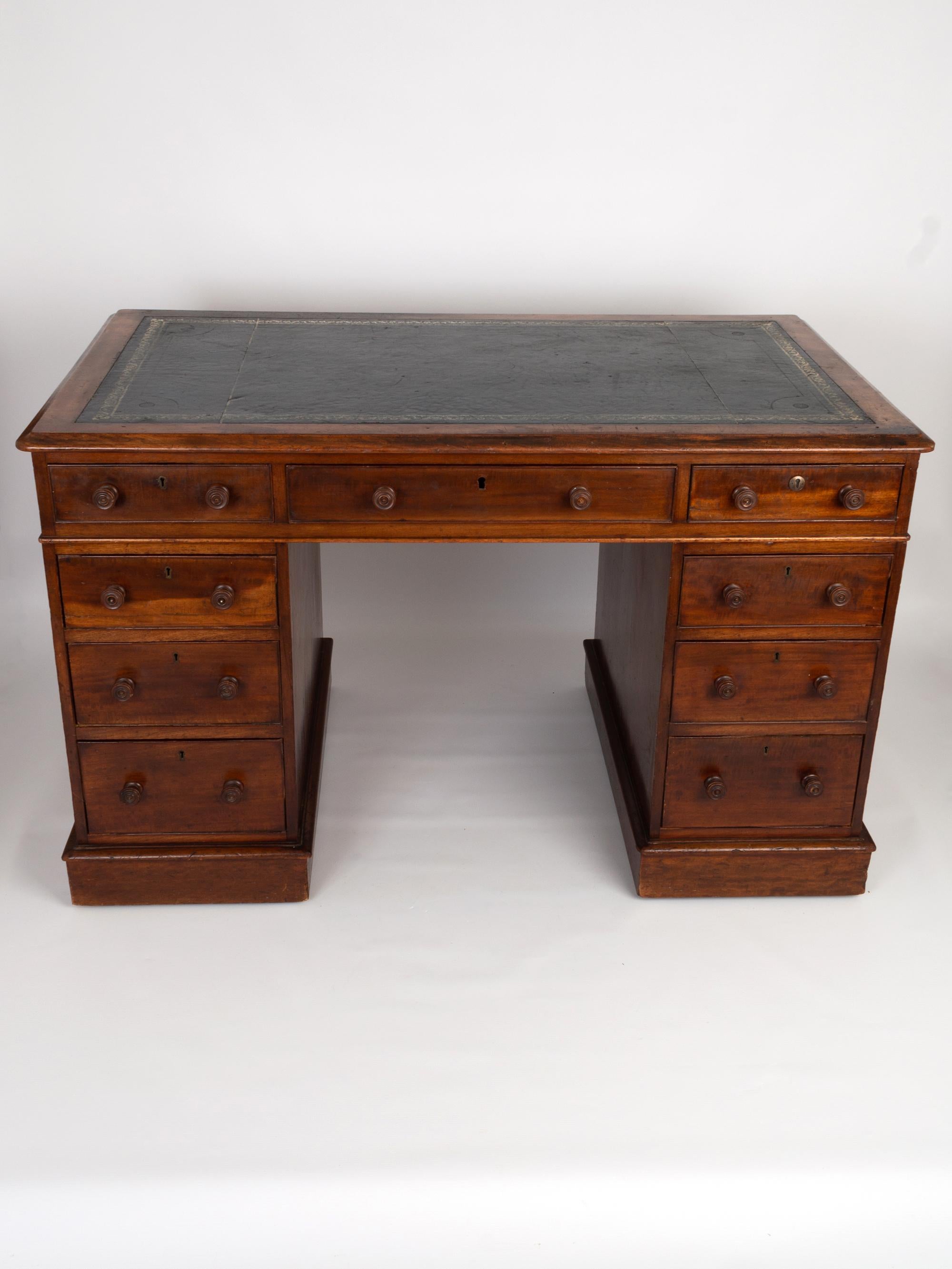 A superb English antique Victorian mahogany pedestal desk dating from C.1850. 
The moulded writing surface has a tooled blue leather finish. The central drawer beneath is flanked by four drawer pedestals with turned mahogany handles and brass