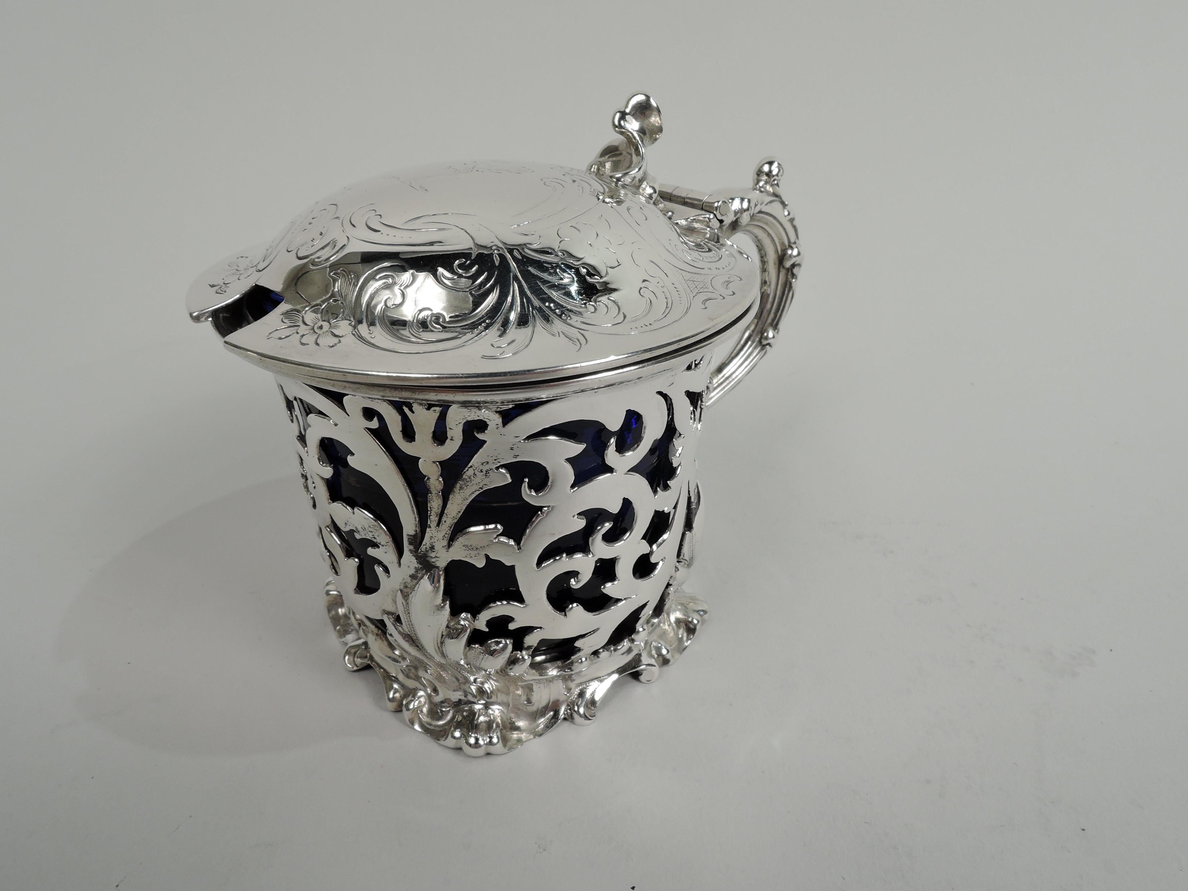 Victorian Rococo sterling silver mustard pot. Made by Edward, John, and William Barnard in London in 1845. Open sides with leafing scrollwork applied at base with leaves forming irregular skirted foot. Cover hinged and solid; top domed and with