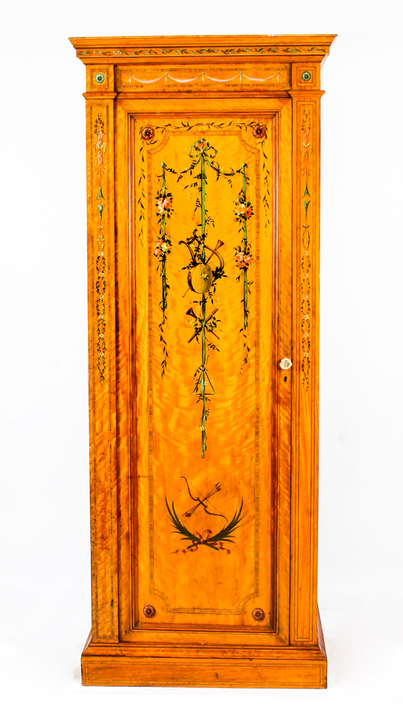 This is an impressive and rare antique English late Victorian Sheraton style satinwood wardrobe, circa 1880 in date.
 
This wonderful wardrobe is made from the finest quality satinwood and features magnificent hand painted ribbon-tied garlands,
