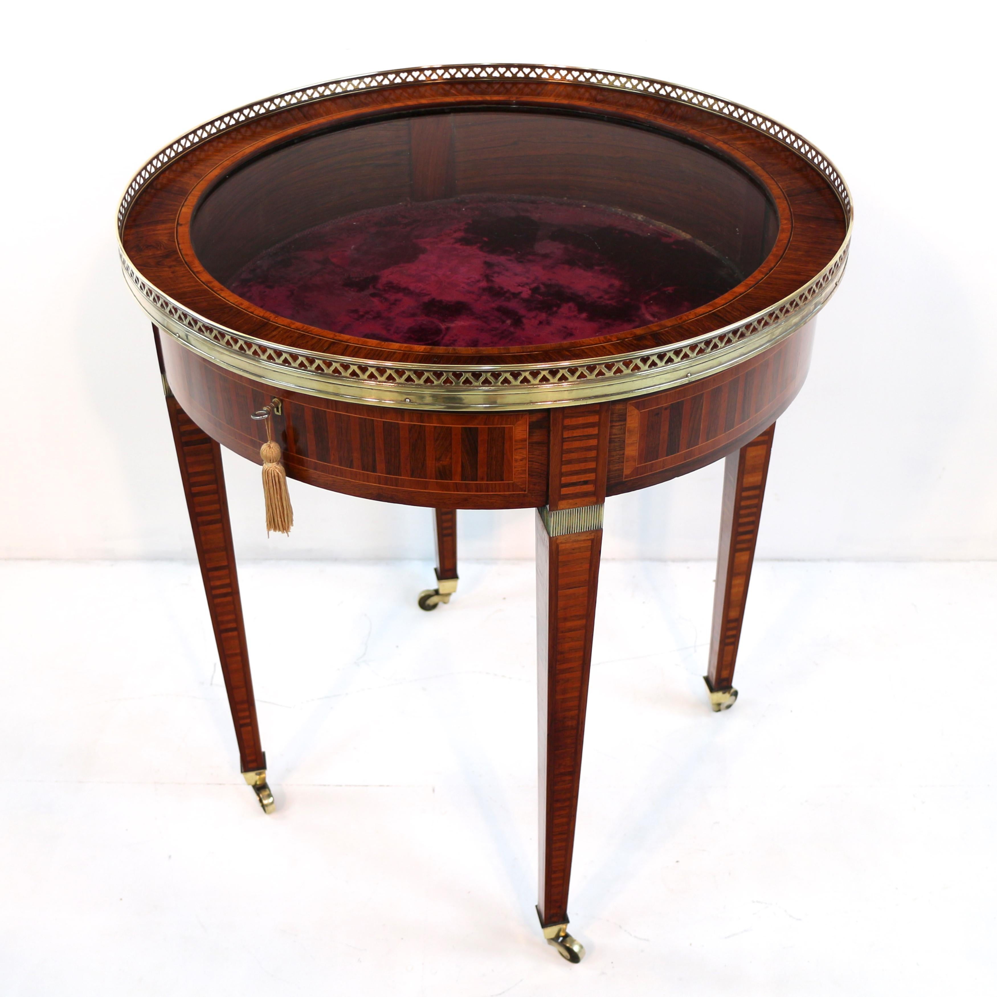 A superb quality English Victorian Sheraton Revival rosewood, parquetry inlaid and brass mounted bijouterie table dating to circa 1880. The circular hinged top with rosewood and satinwood crossbanding with box and ebonies stringing within a low
