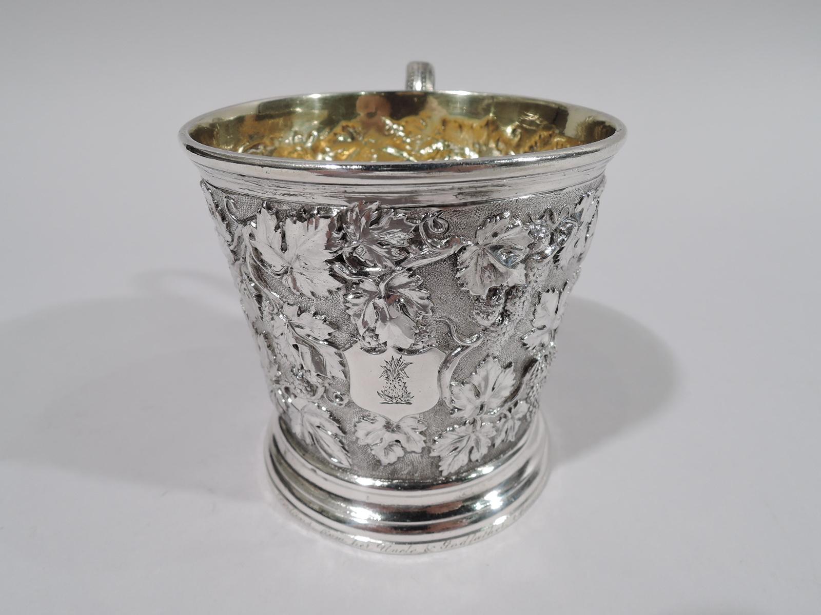 Victorian sterling silver baby cup. Made by John Samuel Hunt in London in 1856. Gently tapering sides, and plain skirted foot and molded rim. High-looping vine handle. Repousse fruiting berry vine on stippled ground. Applied shield engraved with
