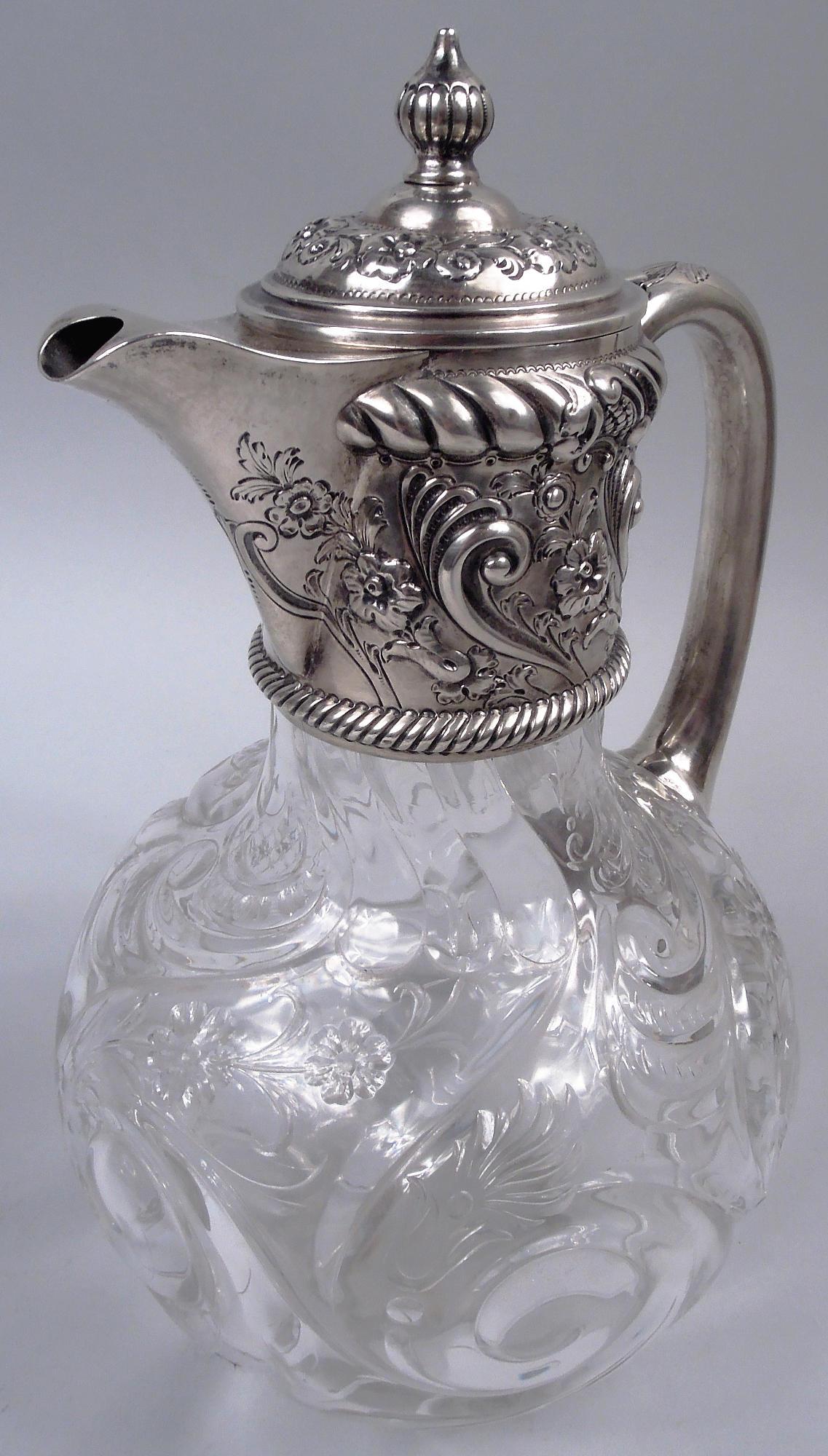 Victorian sterling silver and rock crystal-cut decanter. Made by John Grinsell & Sons in Birmingham in 1892. Globular crystal bowl with flowers and leaves strewn among twisted gadroons and rinceaux. Neck in sterling silver collar with v-spout; cover