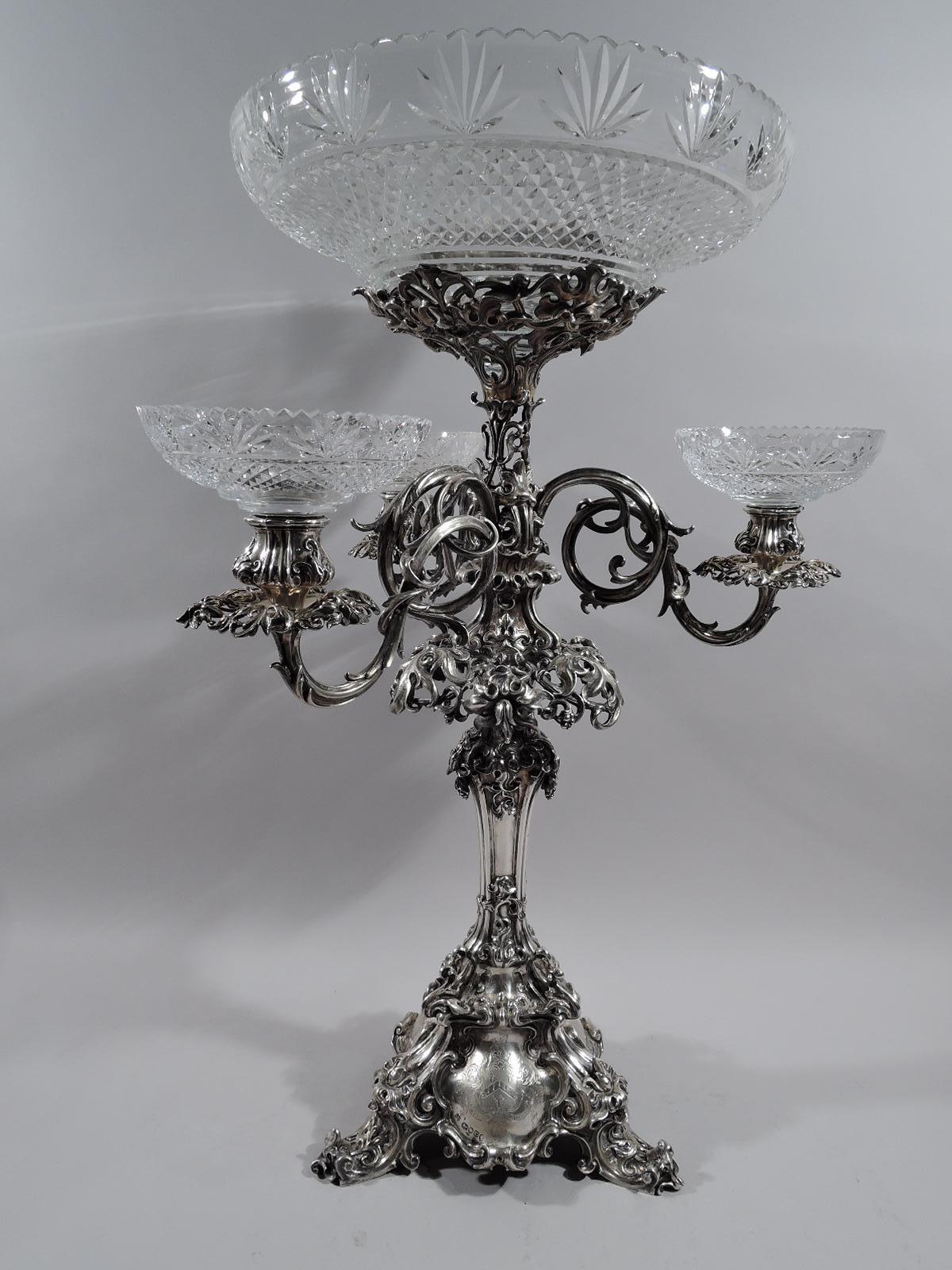 Victorian sterling silver epergne candelabrum. Made by Barnard & Sons in London in 1849.

Shaped shaft with flange and stepped triangular base terminating in 3 scrolled supports. Raised and large central glass basket in support surrounded on 3