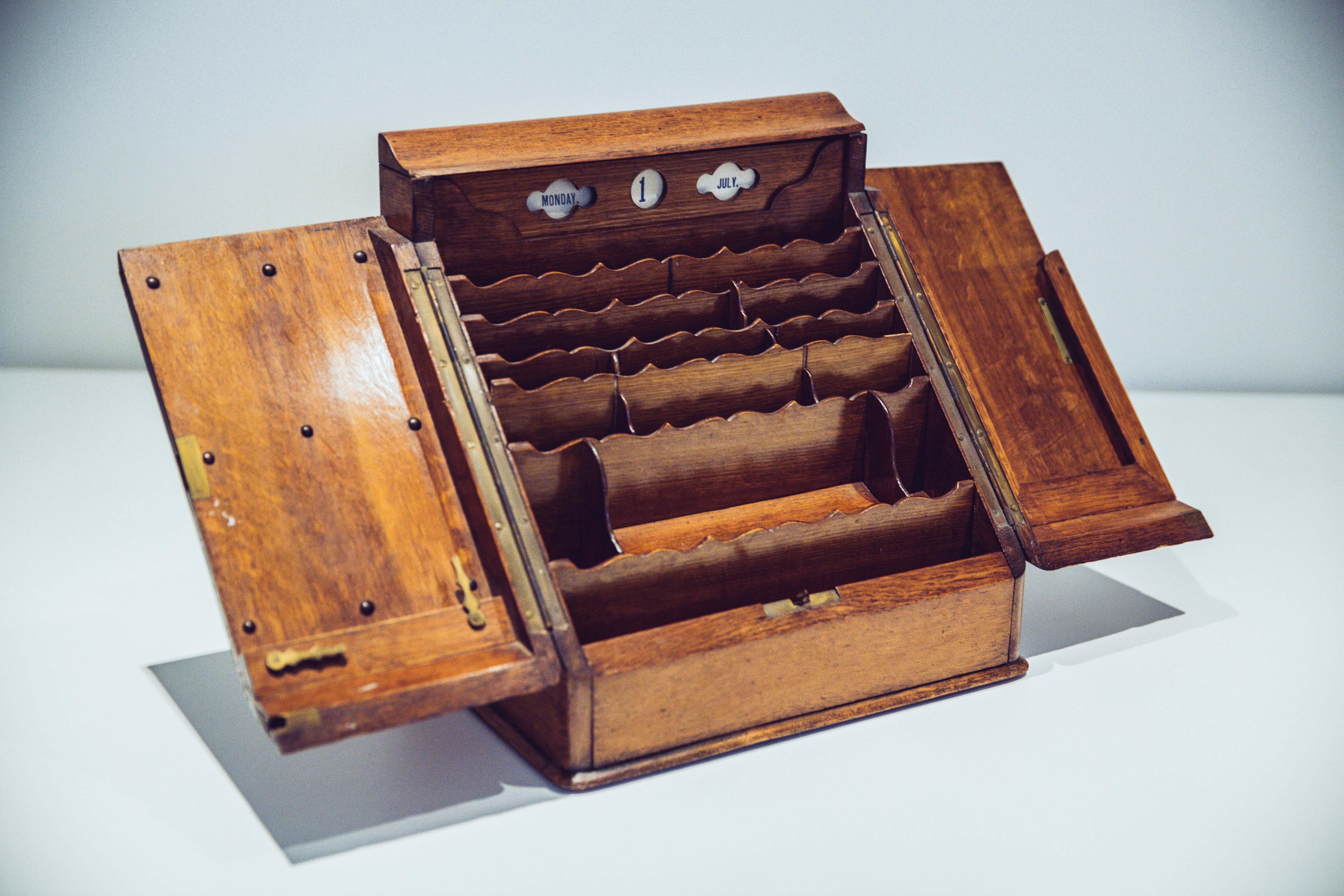 Made in England in the 20th century, this antique walnut desk organizer has its original key and working lock. It is has many compartments and secret hiding places. The top panel holds calendar cards with the days (Monday till Saturday), dates (1st