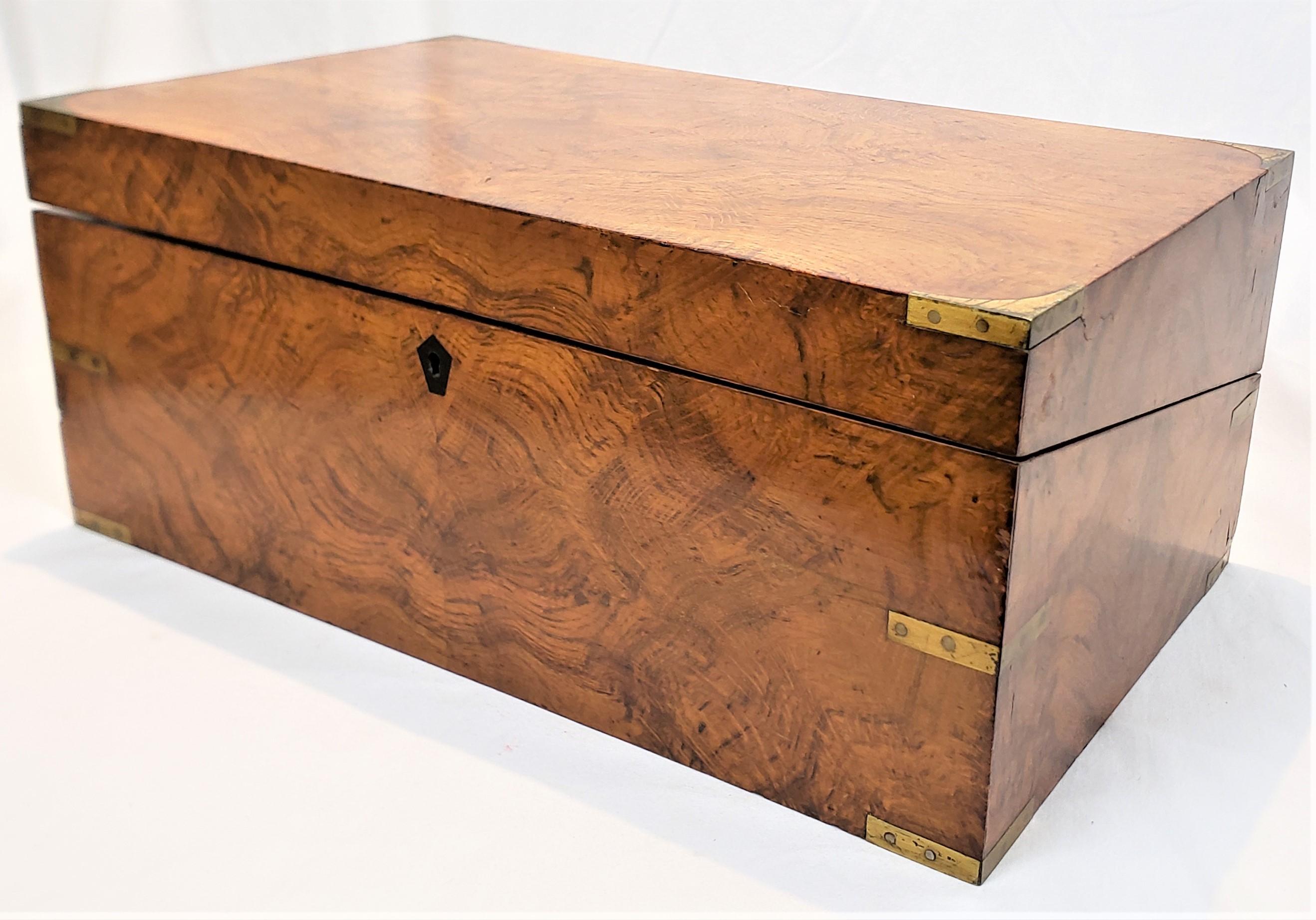 This antique campaign box is unsigned, but presumed to have originated from England and date to approximately 1820 and done in the period Victorian style. The lap desk is composed of walnut with brass mounts and fittings and has a drawer with dove