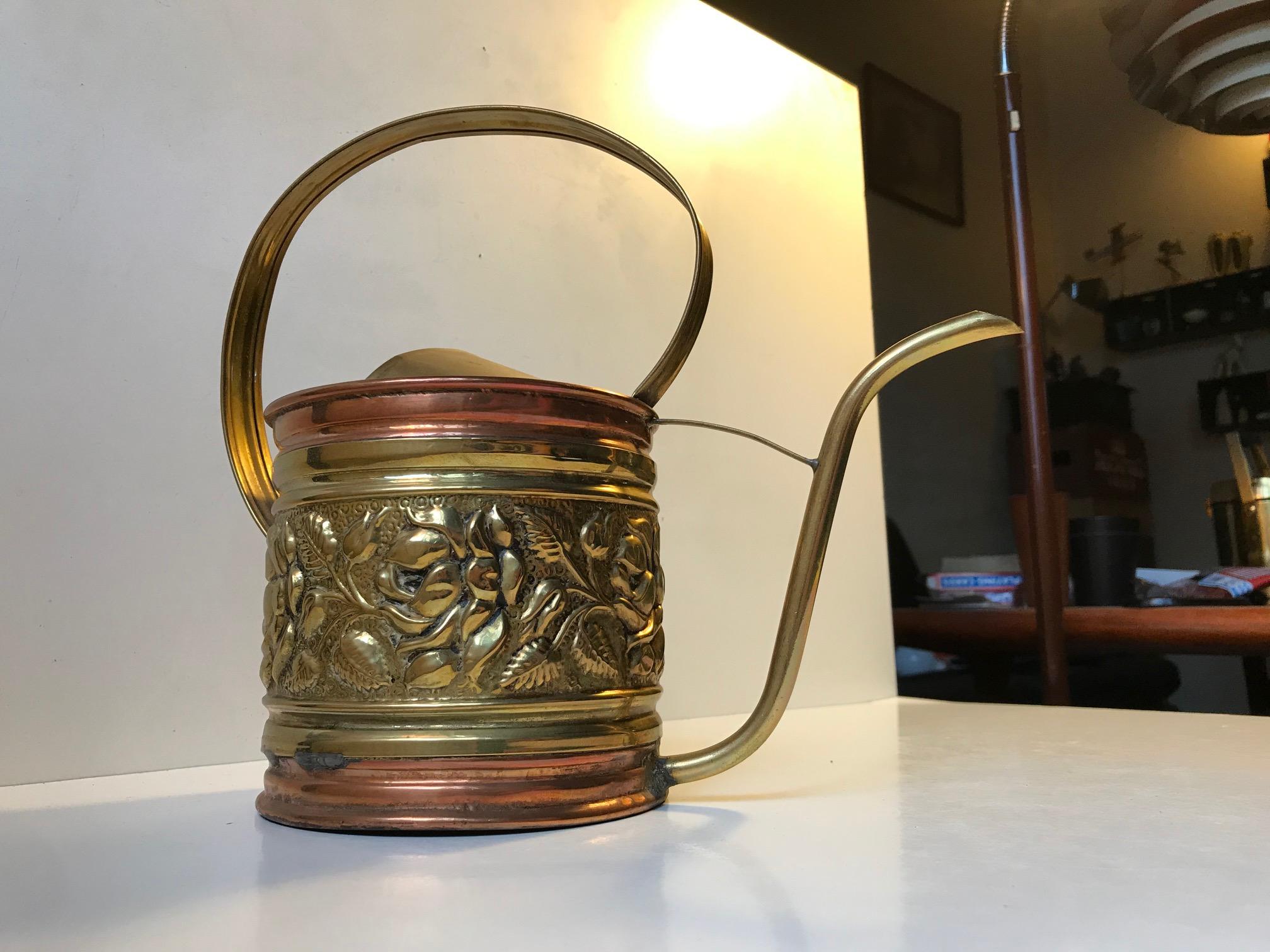 A large copper watering can executed with punched mid-section in brass. Its made in England in the early 20th century. This particular example been loved and it shows several body repairs to keep the water in. It no longer has leaks nor dents or