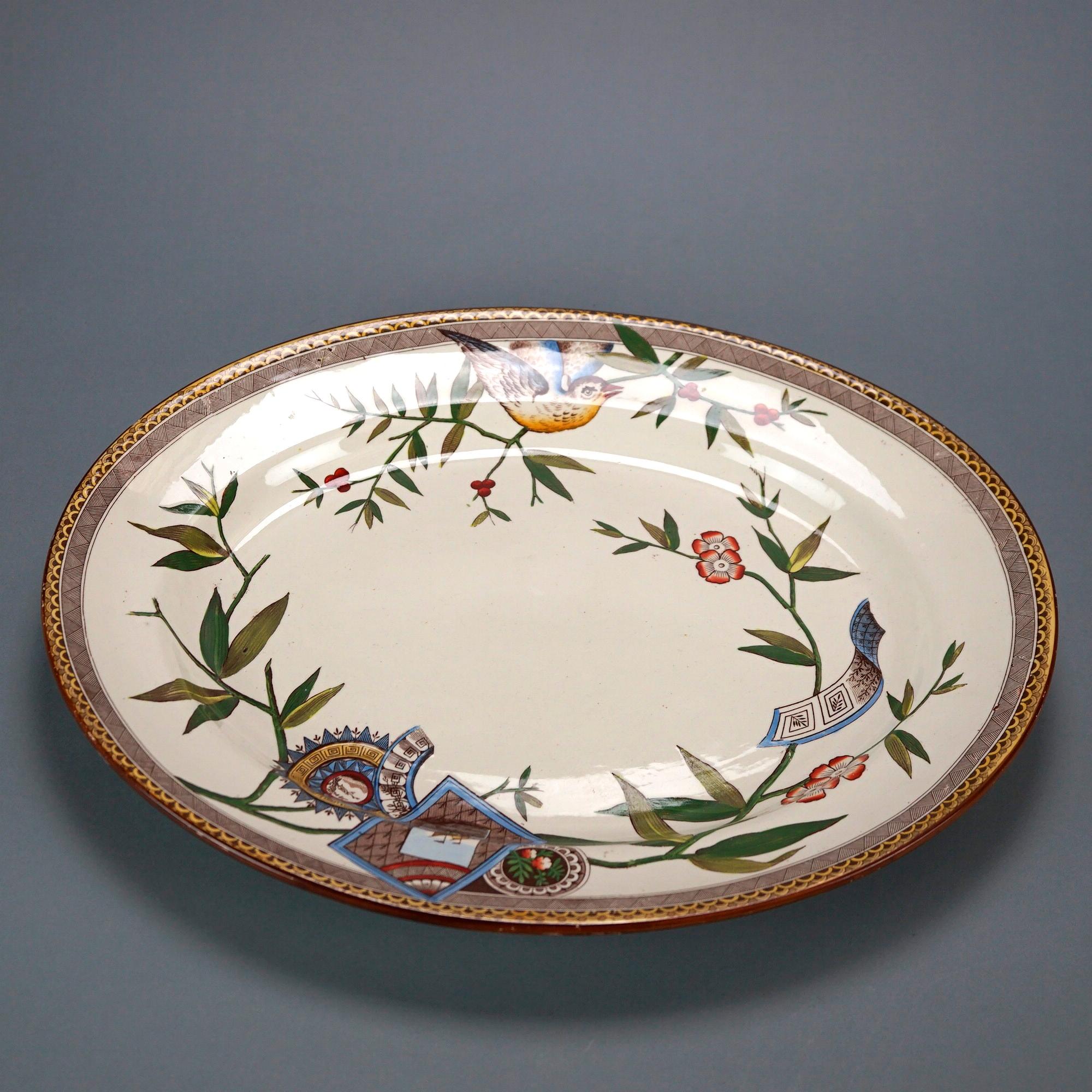 An antique Aesthetic Movement serving platter by Wedgwood offers porcelain construction in oval form with bird and garden elements, gilt highlights throughout, en verso maker mark as photographed, 19th century

Measures- 18.25'' H x 14.5'' W x