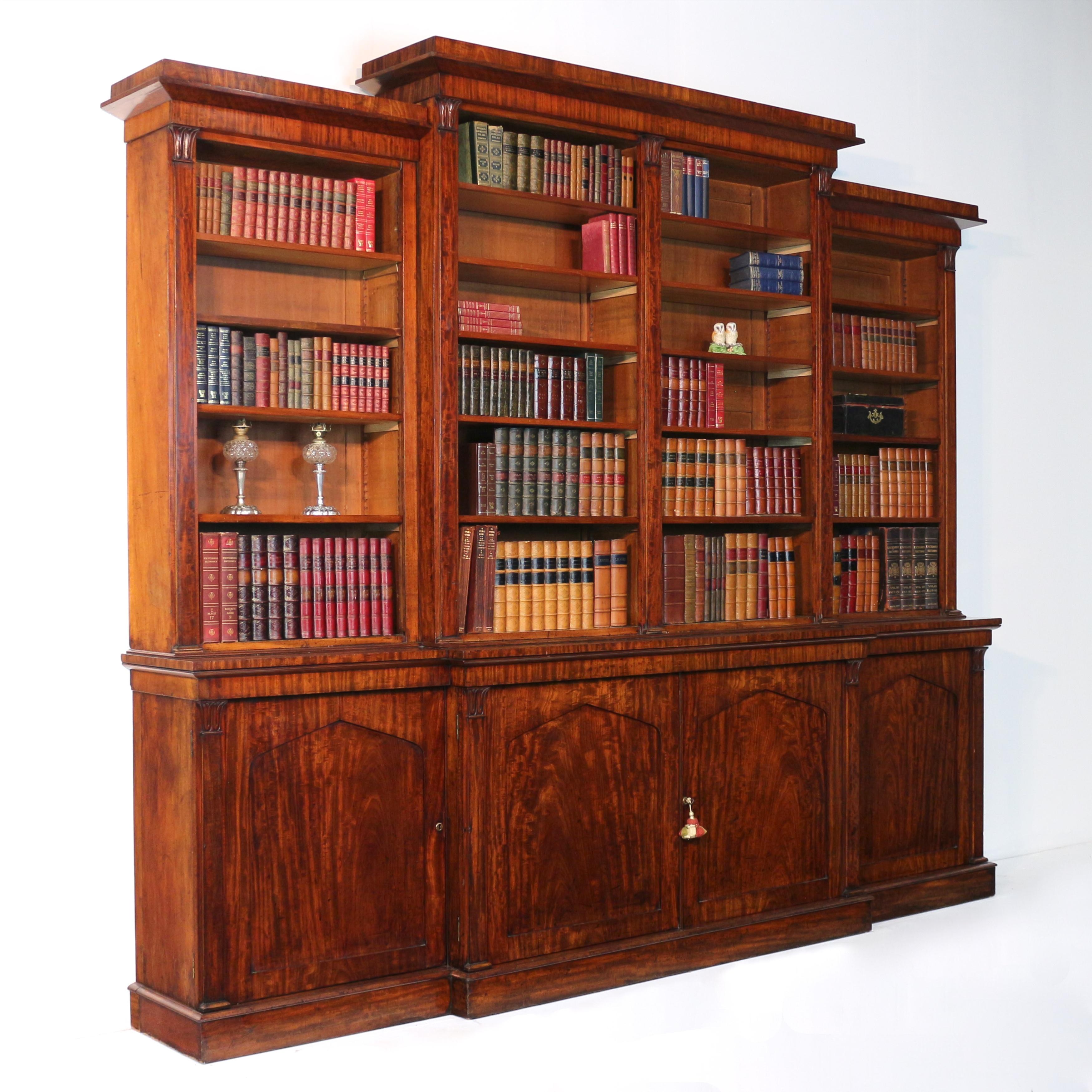An impressive flame mahogany William IV four door library bookcase with fantastic original rich colour and striking grain, it featured lotus bud carvings to the top of tapering flat pilasters to the top and base. With a square cornered moulded