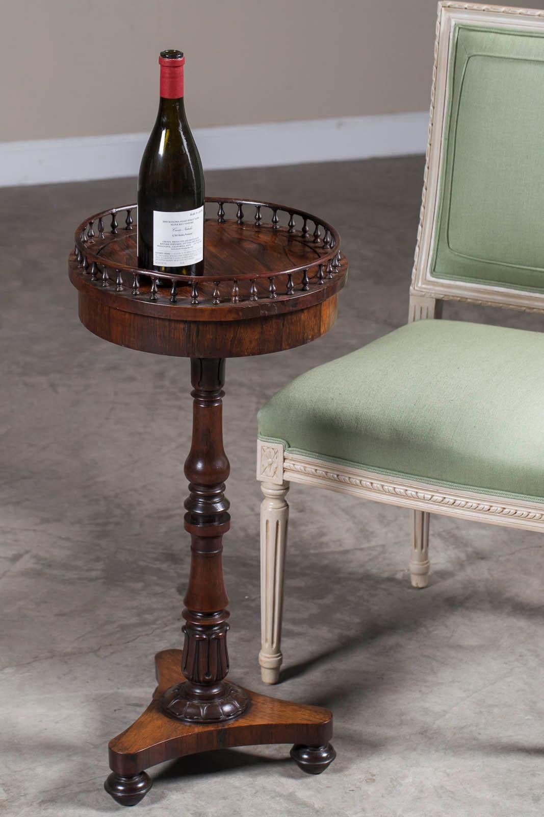 An antique English William IV period rosewood mahogany wine table from England, circa 1835 having a raised gallery edge. This table displayed a prized bottle of wine or port for enjoyment after dinner in a well appointed home. The tall and slender