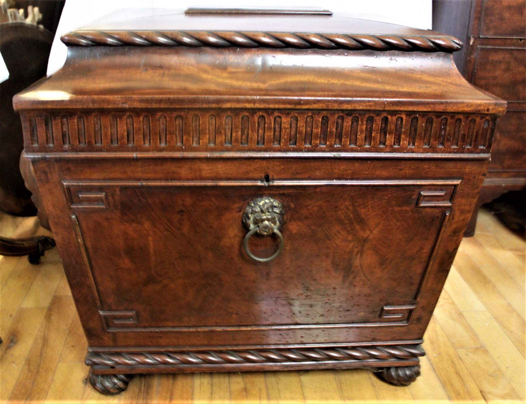 This antique English flamed mahogany wine cooler dates to circa 1830 and done in the period William IV style. The cabinet is done in flamed mahogany with rope motif border decoration on the raised top and bottom edges and used to accent the bun