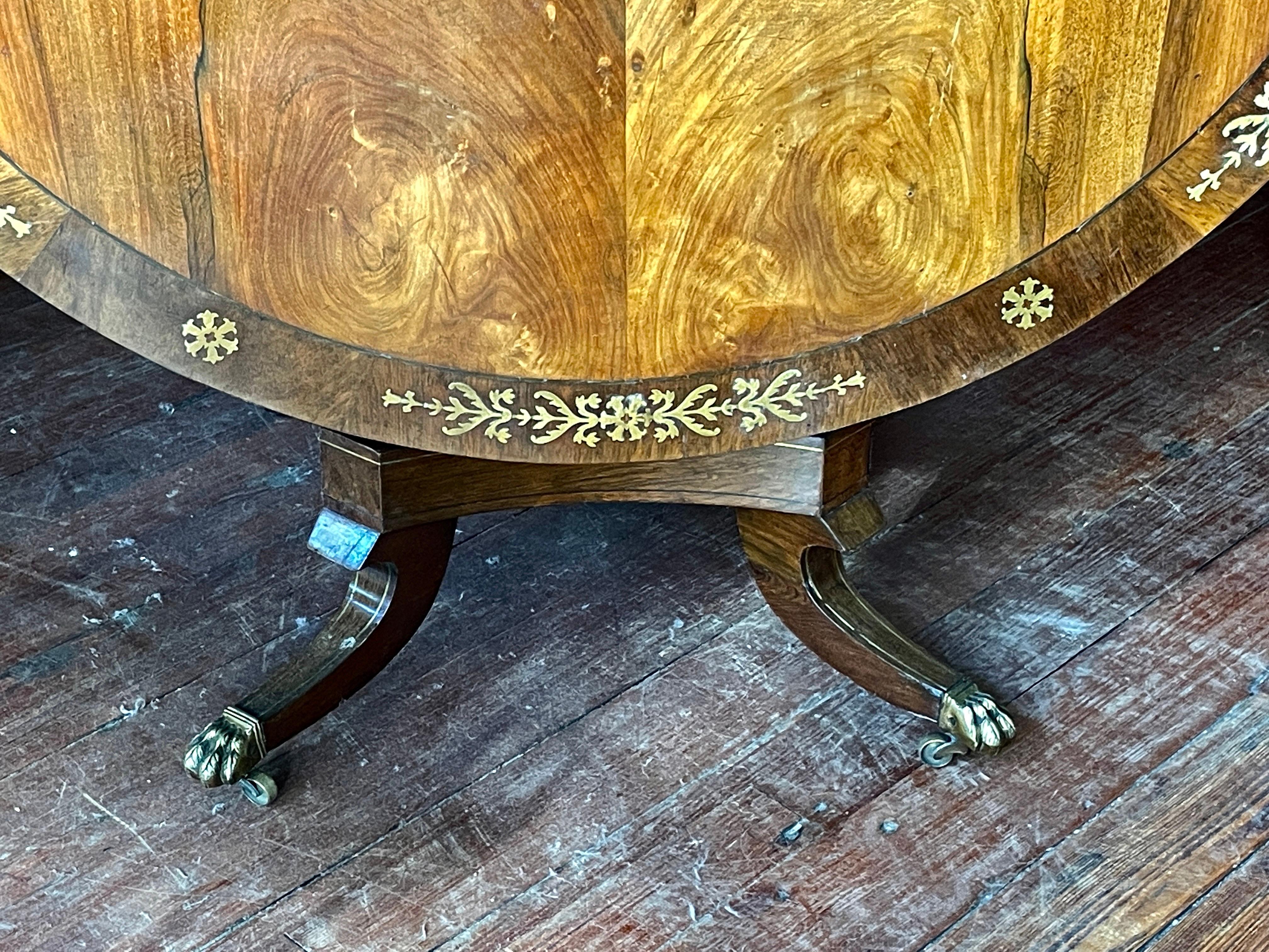 An extraordinary Antique English period Regency brass inlaid Rosewood Circular Tilt-Top Center or Dining Table with a walnut crossbanding. Please note the exceptional hand cut brass inlay around the walnut crossbanded border and the fabulous