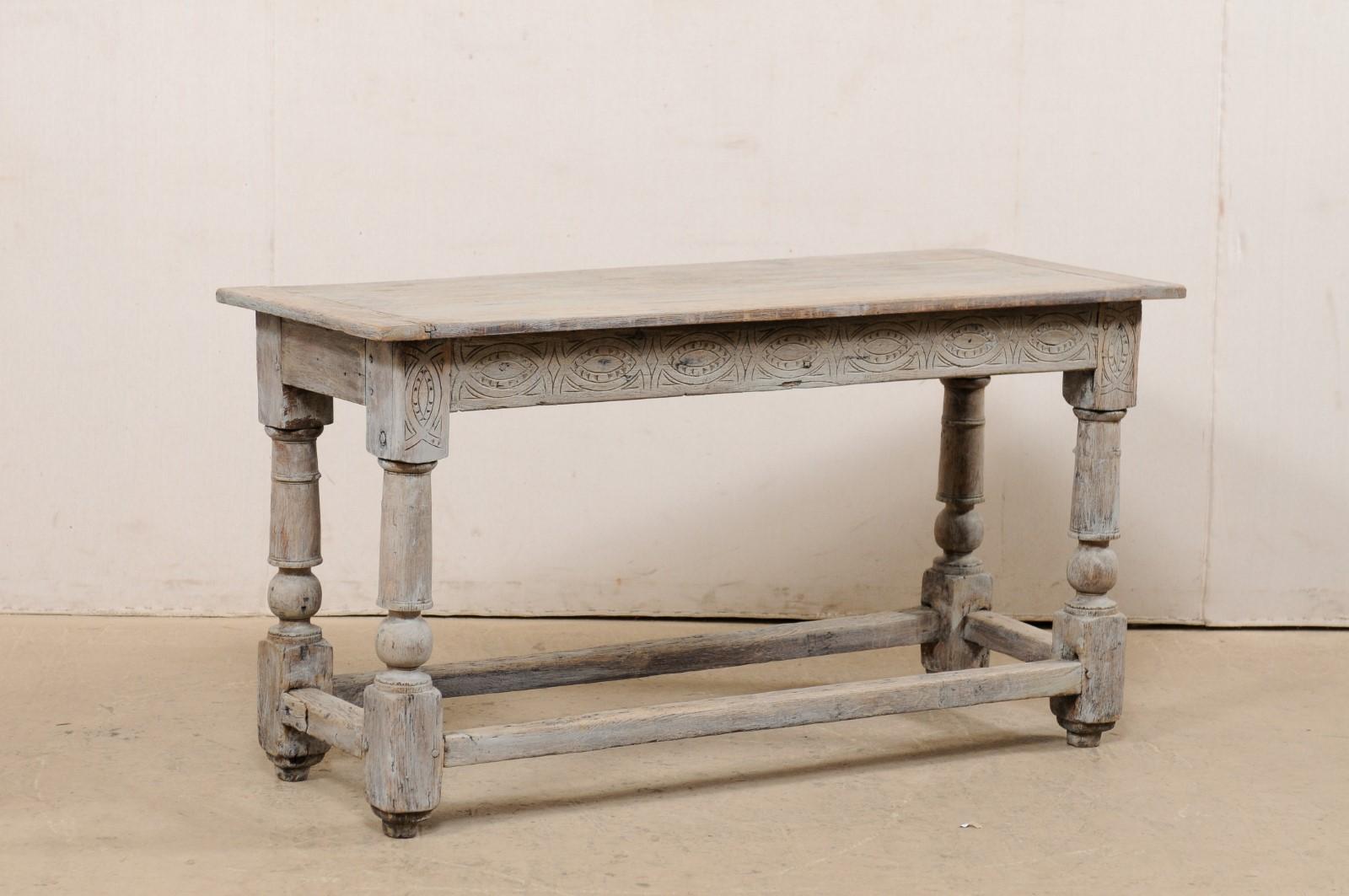 An English carved and painted wood console table from the turn of the 18th and 19th century. This antique table from England features a rectangular-shaped, plank-board top which overhangs the apron below which is carved along its longer, front side