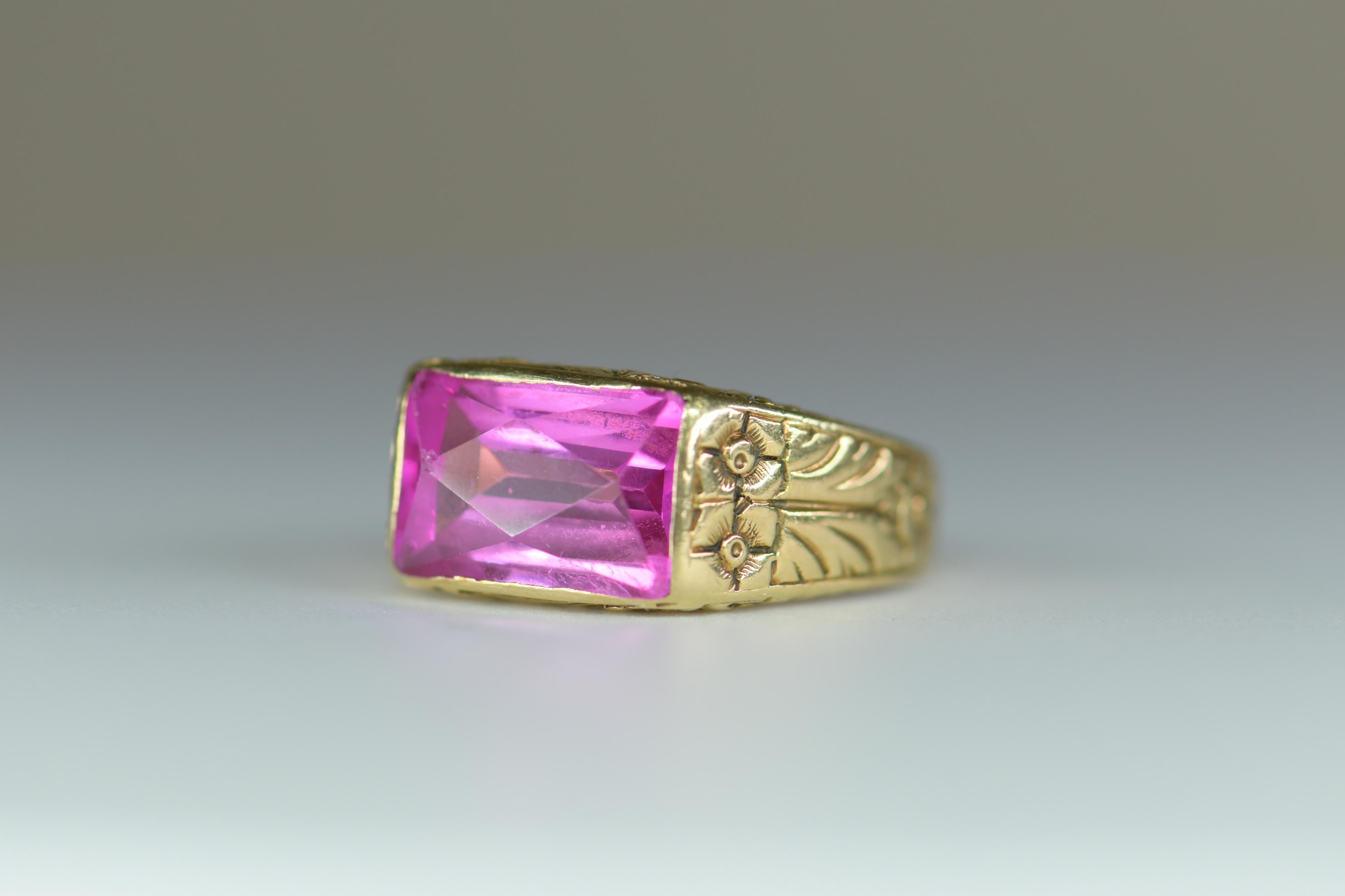 Antique engraved floral design ring features a vibrant 12mm x 7mm pink quartz. A bright electric teal pink emerald-cut pink quartz is beautifully presented in engraved gold.  The yellow gold band features a scrolling floral design engraved around