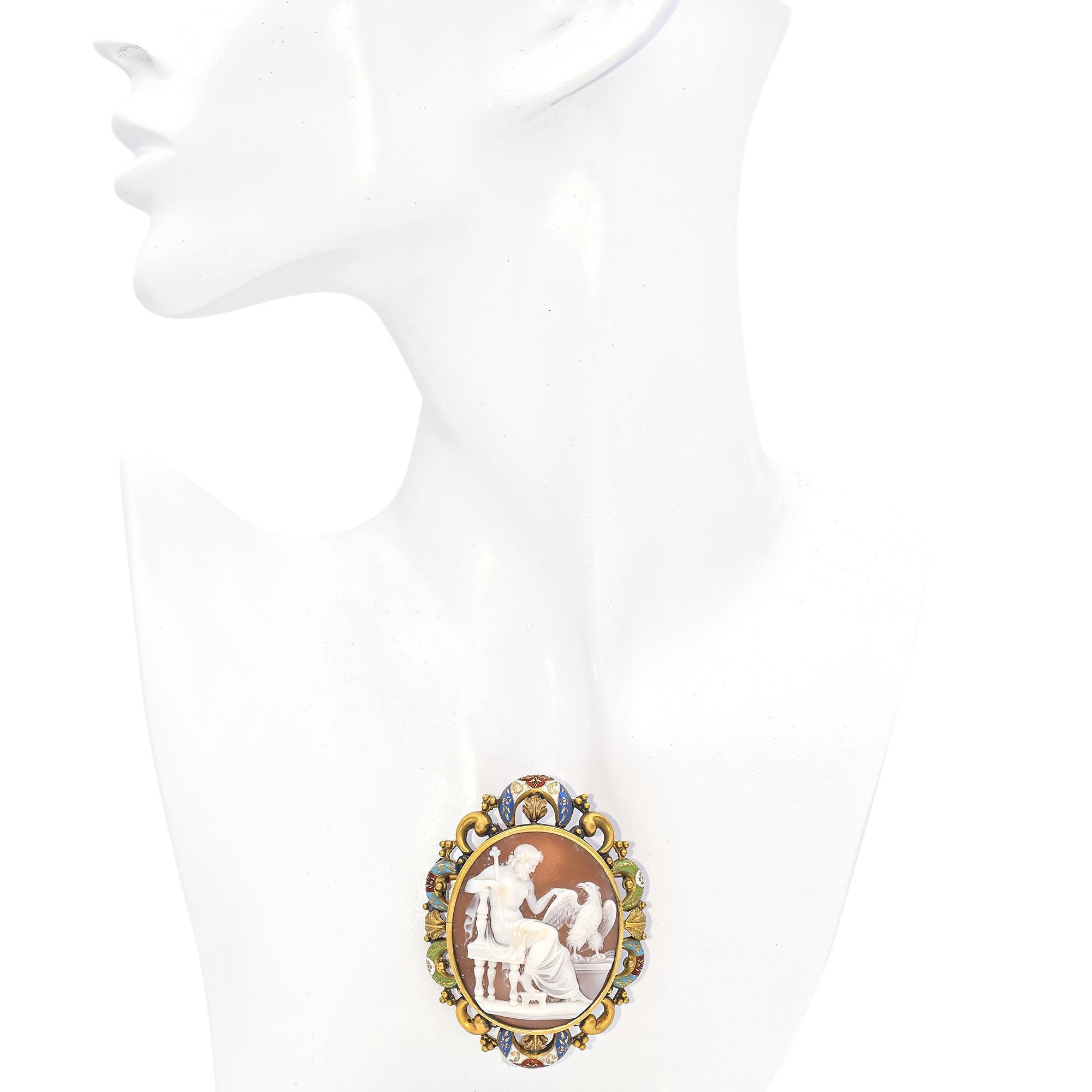 Cette broche complexe présente un camée détaillé serti dans une monture en or. Le camée en sardonyx, incroyablement détaillé, représente une rare scène mythologique de Zeus sur son trône, caressant un aigle. Le cadre est orné d'un travail d'émail