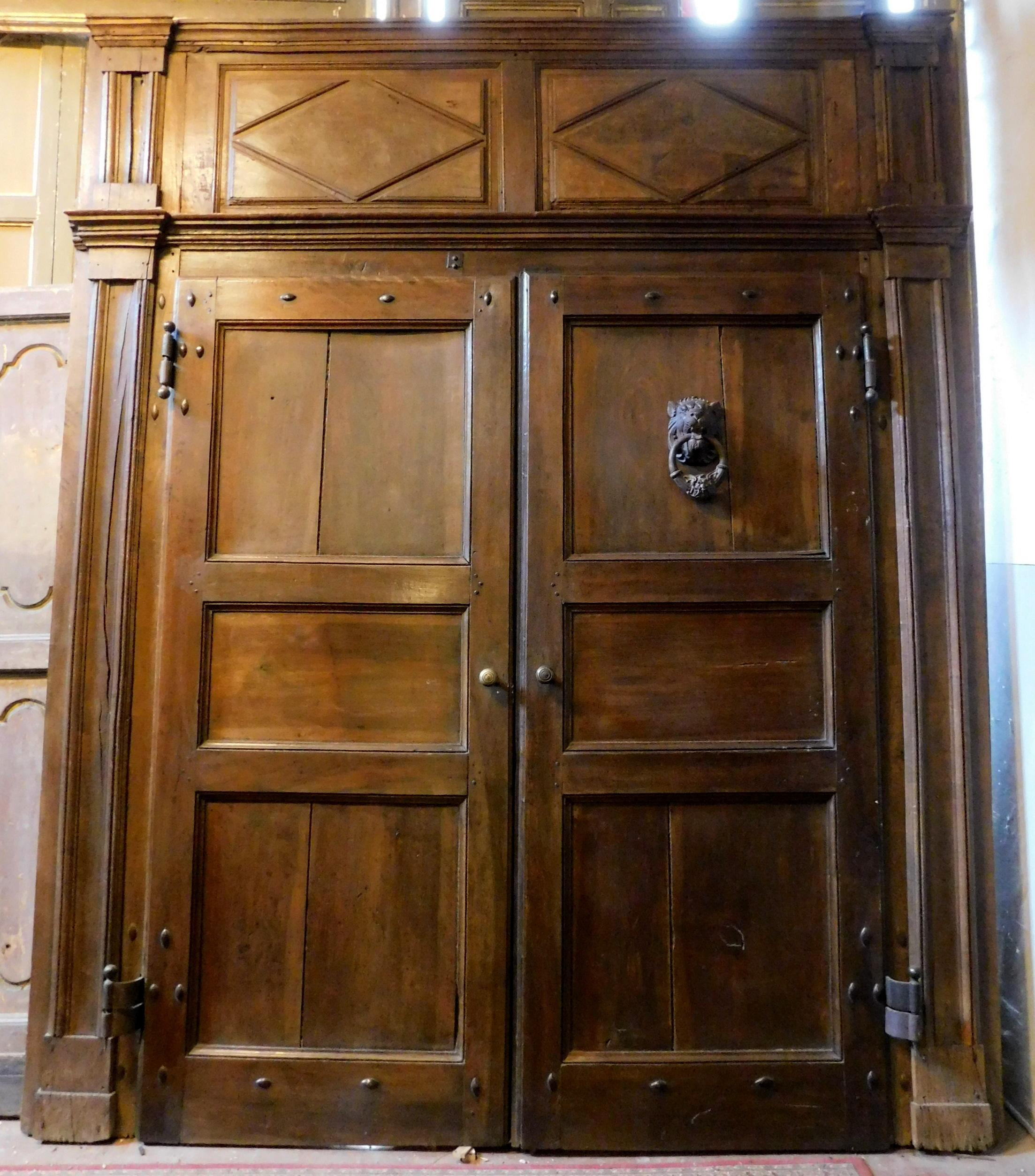 Ancient and important entrance door, main entrance, hand-carved in precious walnut wood in patina, complete with its original portal and carved with columns, still retains all its original irons with knockers, locks and handles, built completely by