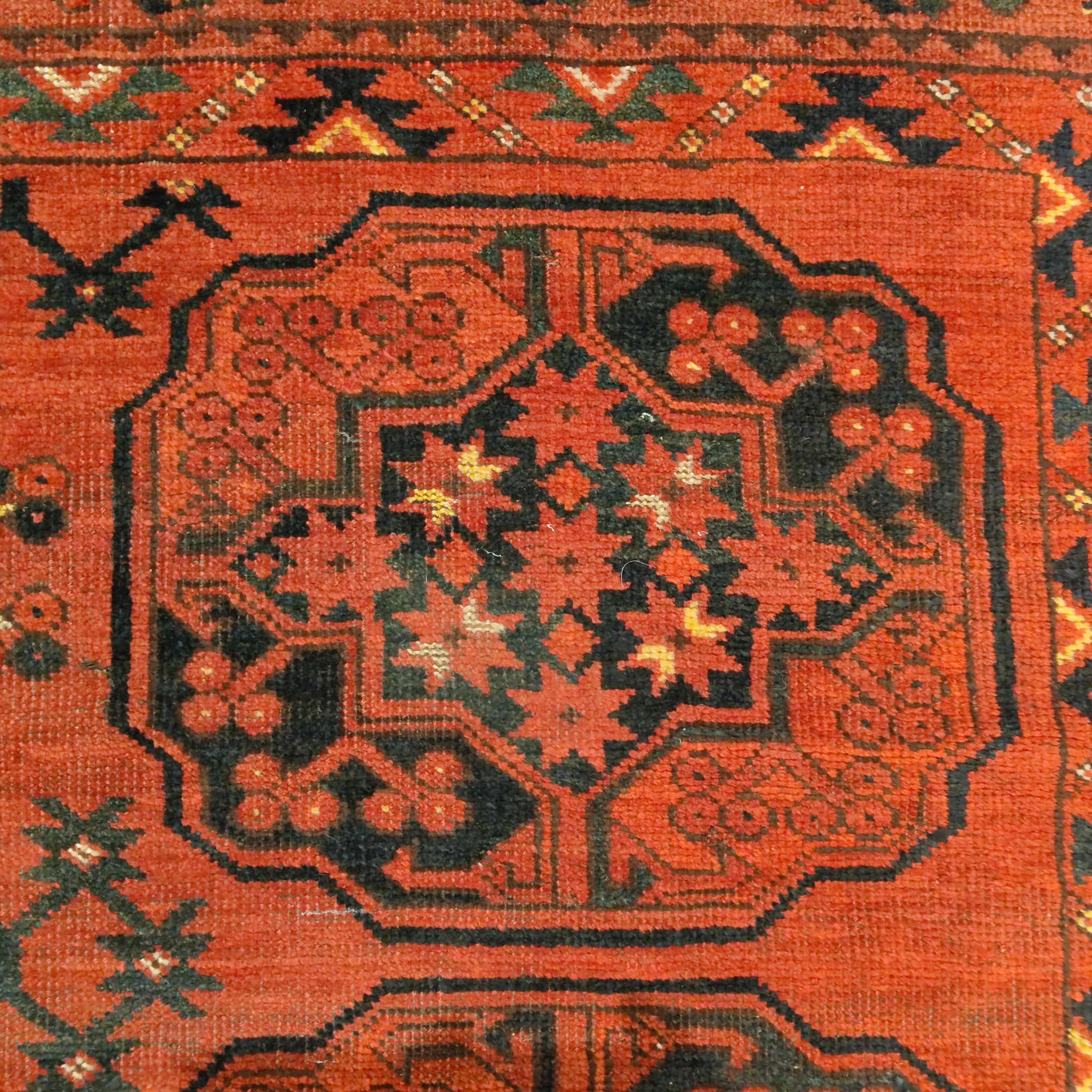 A classic Ersari Turkmen tribal rug, woven in the Bokhara Emirate, with a pattern composed of three vertical rows each containing five so called 'gulli gul' elements on a warm mahogany red background. The square format is rather unusual for Turkmen