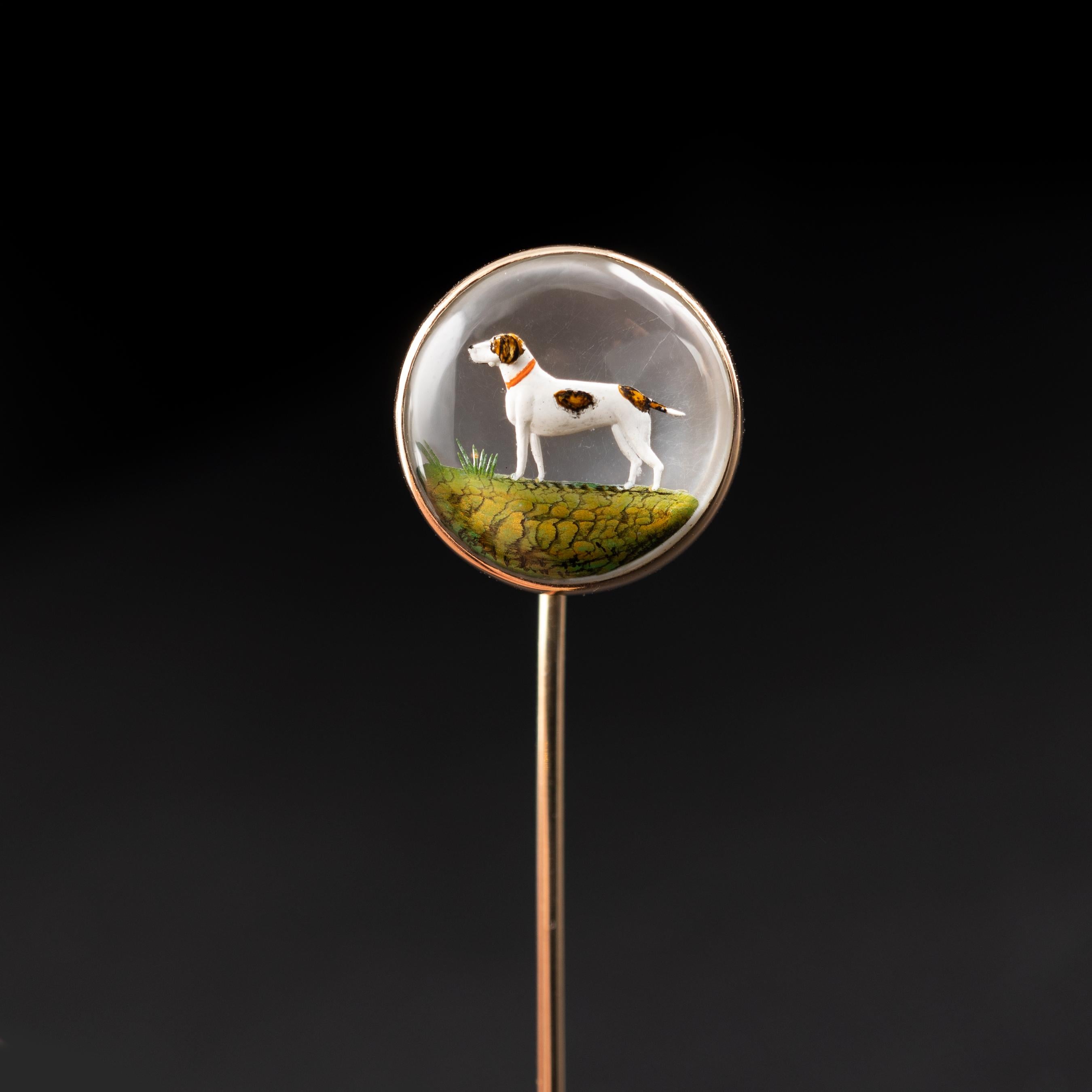An outstanding antique Essex Crystal stick pin with pointer dog scene, Circa 1900.

The domed crystal displays the white and brown pointer dog with a red collar, standing on green iridescent foliage. The scene has been carved into the back of a