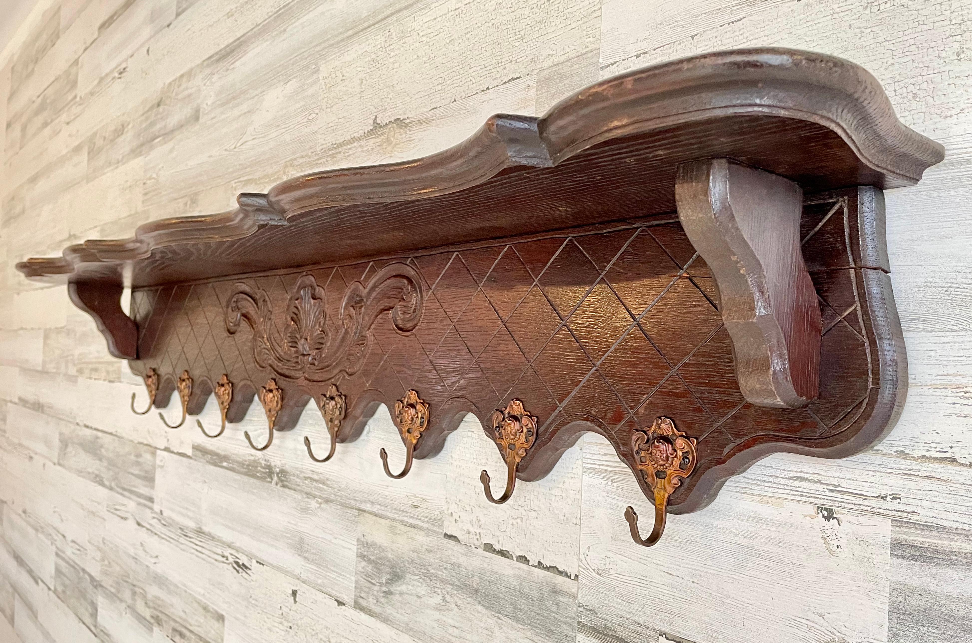 French antique étagère casserole / coat rack. Solid oak with decorative Louis XIV embossed brass hooks for pots, pans, or coats. The top includes a plate groove for display.