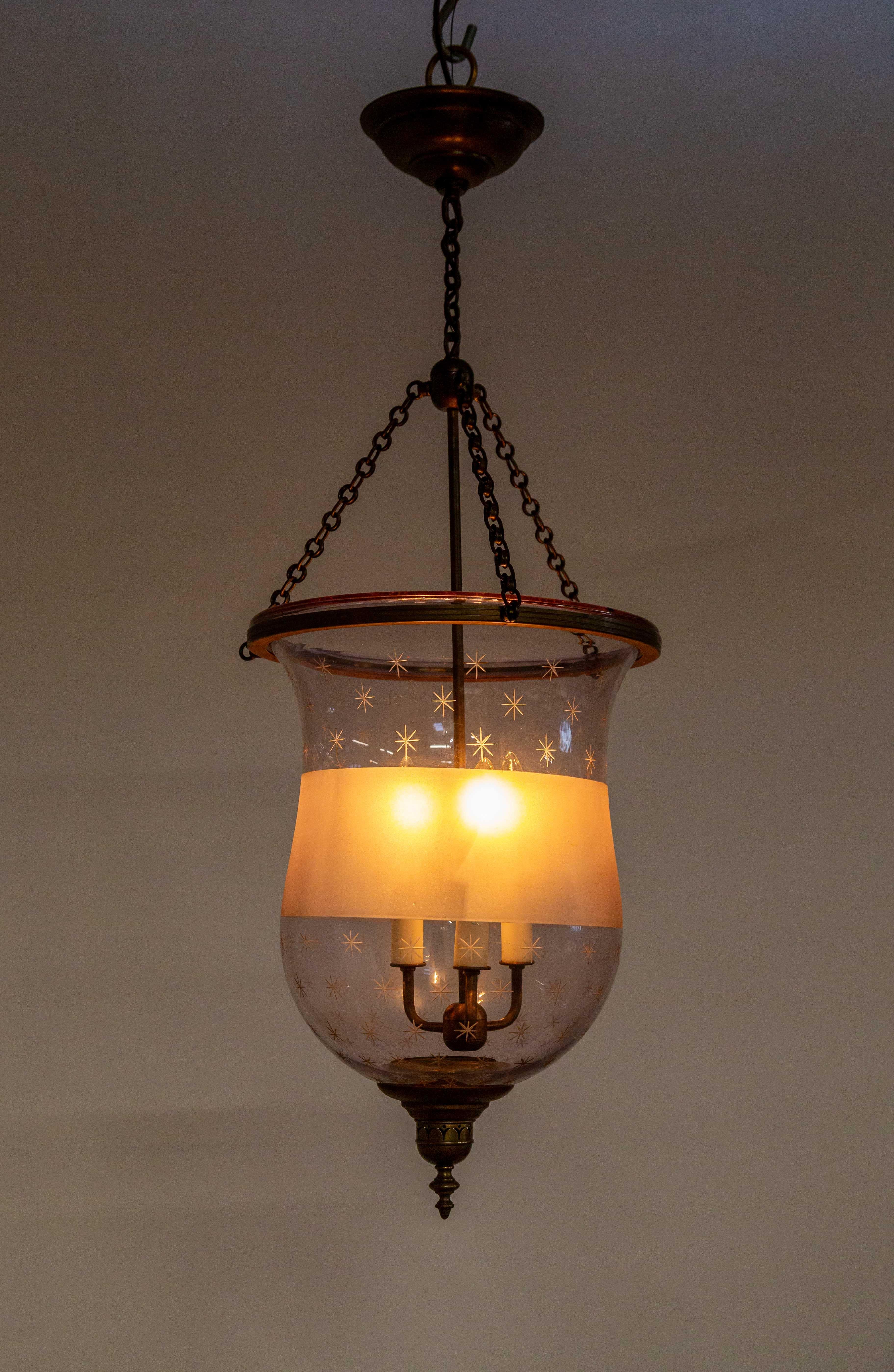 A unique bell jar lantern in late 19th century, amethyst glass with hand engraved stars and a frosted band that diffuses the light magnificently. Newly made with three candlestick lights, bottom finial, stem and chains. 14