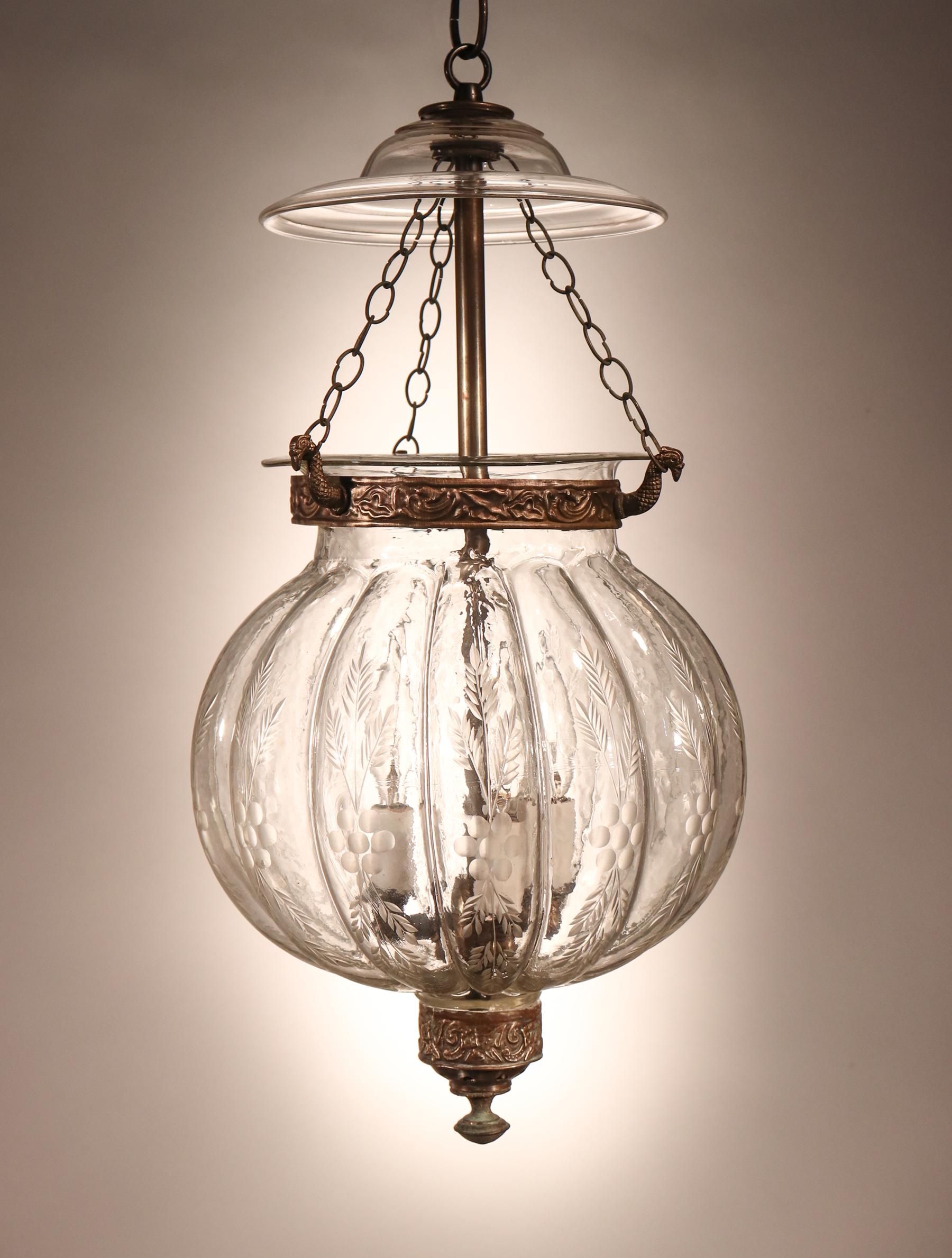 An antique etched melon- or pumpkin-shaped bell jar lantern from Belgium, circa 1890. The quality of the lantern's hand blown glass is very good, with several desirable air bubbles and swirls in the jar. The smoke bell/lid, brass finial, and brass