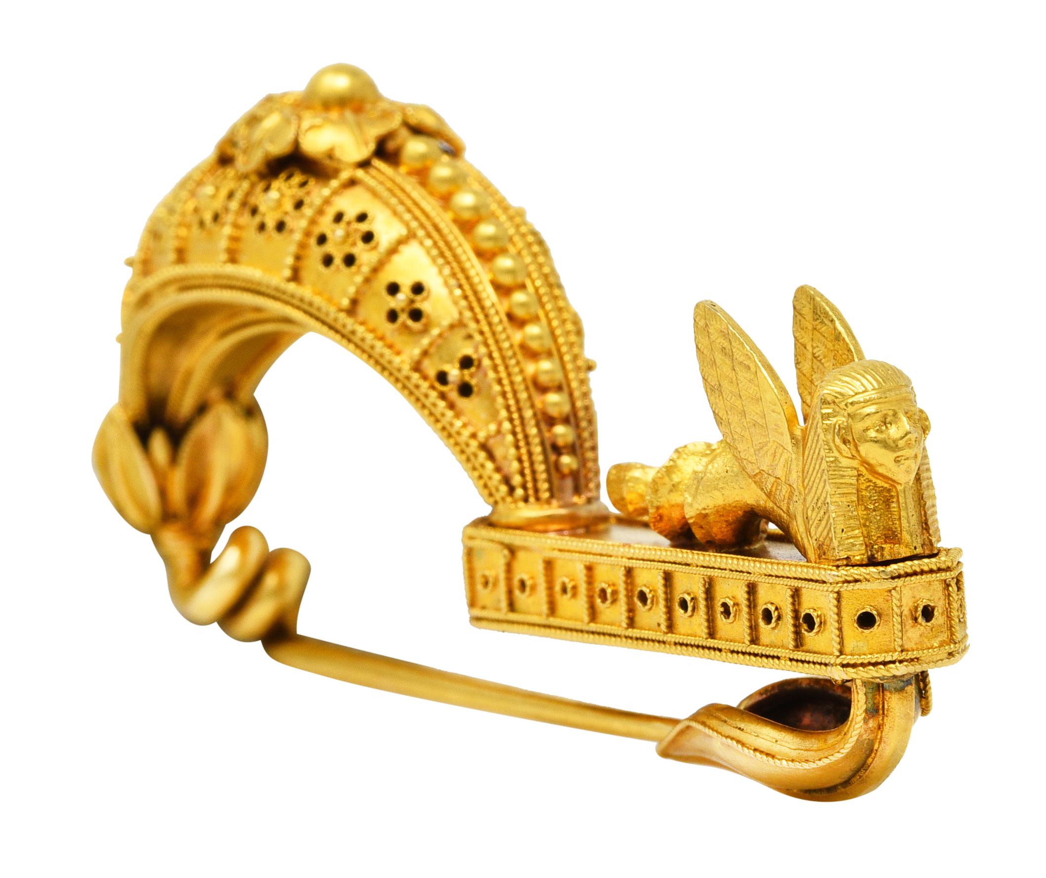 Brooch is designed as a crescent form arching to connect to an elongated octagonal platform. Crescent is decorated with granulation, filigree, pierced floral motifs and rendered foliates. Octagonal platform features decorative piercing and filigree
