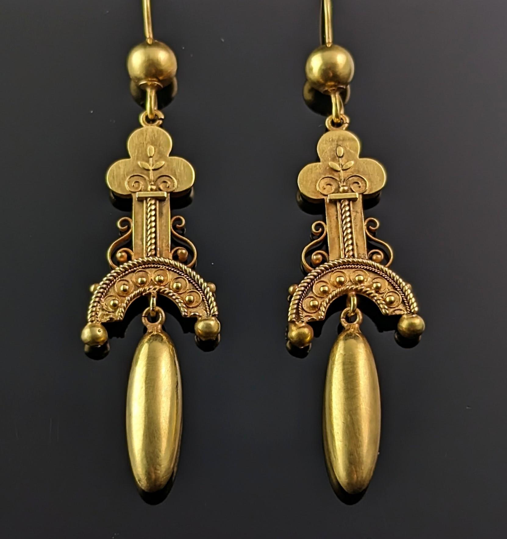 A truly stunning pair of antique 15ct gold Etruscan revival style earrings.

They are dangly earrings the tops made up of a trefoil or club shaped column with delicate cannetille detailing and wirework to the sides.

Suspended from here there is a