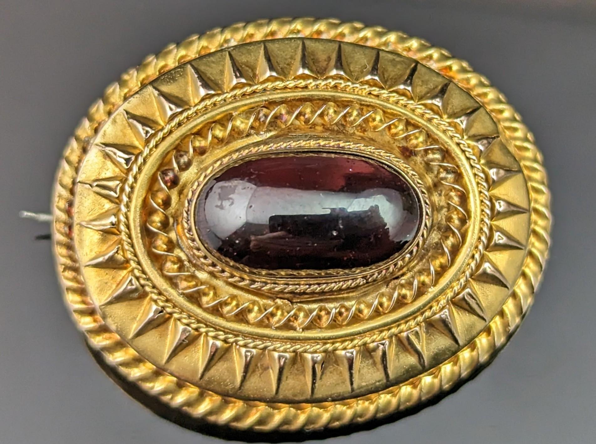This antique Mid Victorian Garnet Cabochon brooch is delightfully beautiful.

Rich buttery 9ct bloomed yellow gold, the attractive Etruscan revival style featuring a repousse star or sunburst design with rope twist highlights.

This houses a big,