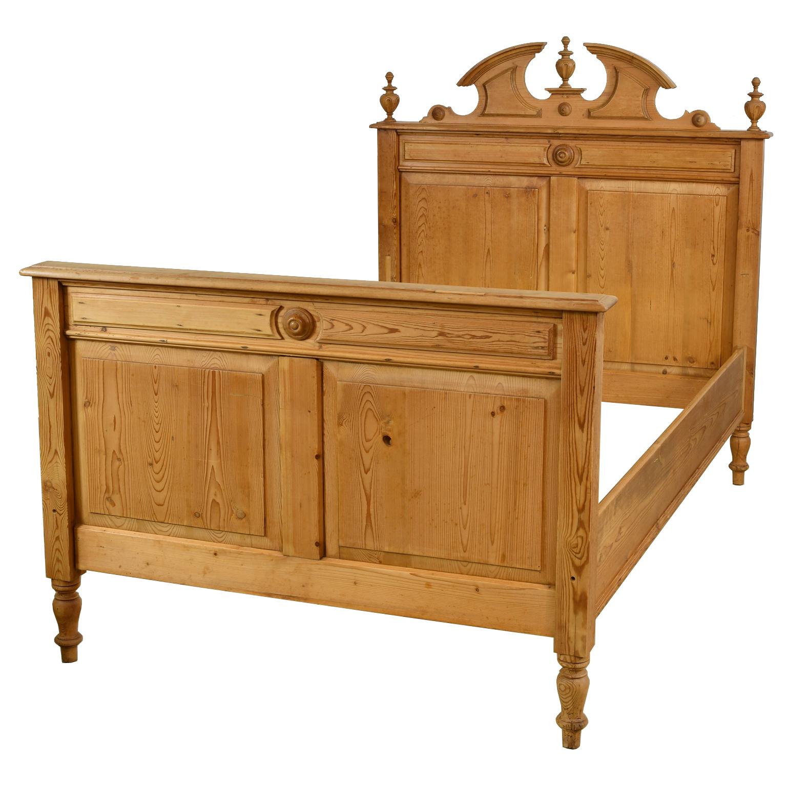 An exceptionally beautiful Grunderzeit bed in European pine with raised panels and bullseye rosettes on headboard and footboard, and a carved split-pediment top embellished with moldings and carved scepter finials. Bed rests on turned legs, Germany,